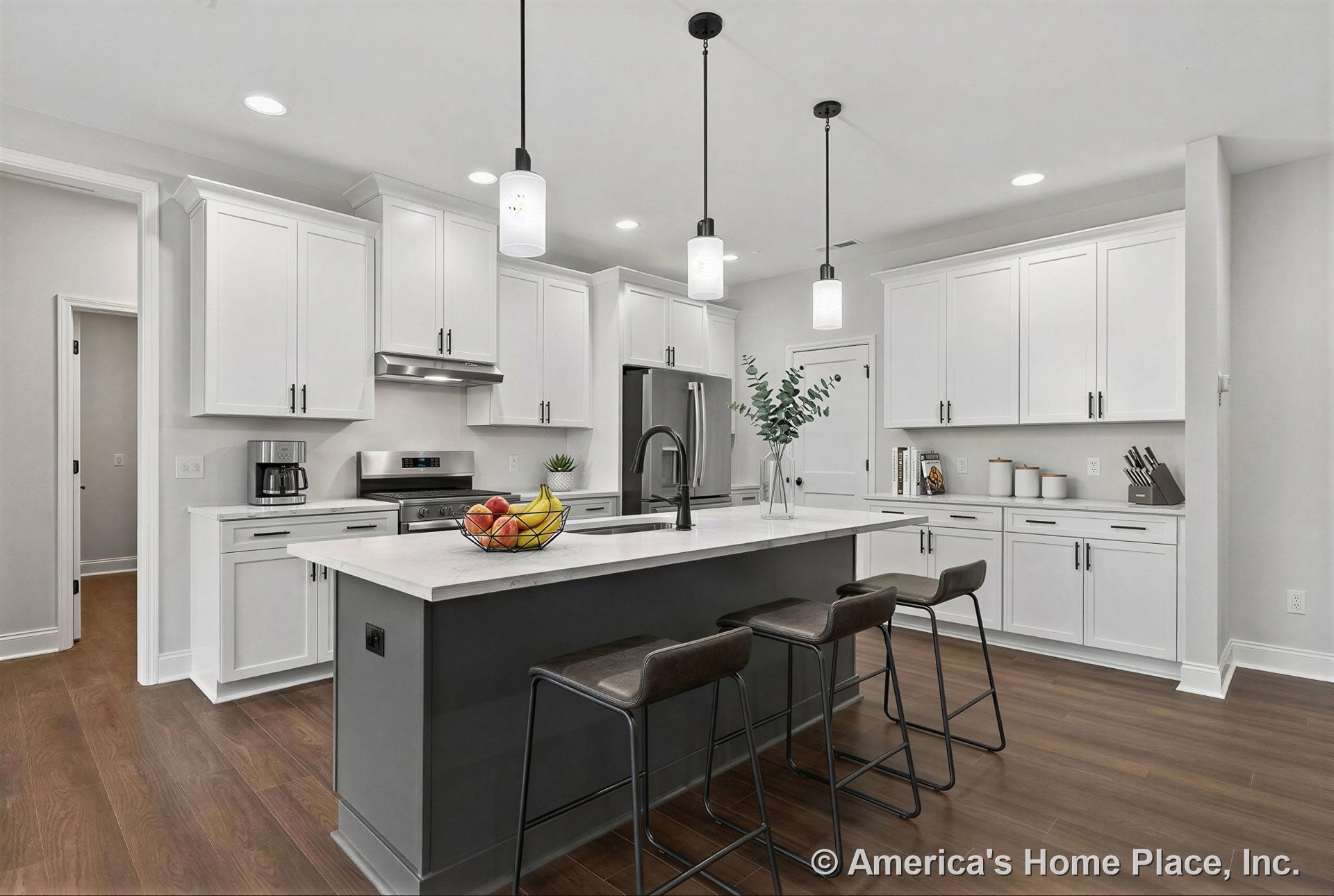 White shaker cabinets and built-in storage, large quartz island countertop with undermount sink and gooseneck faucet, stainless steel appliances, pendant lights above island, wood