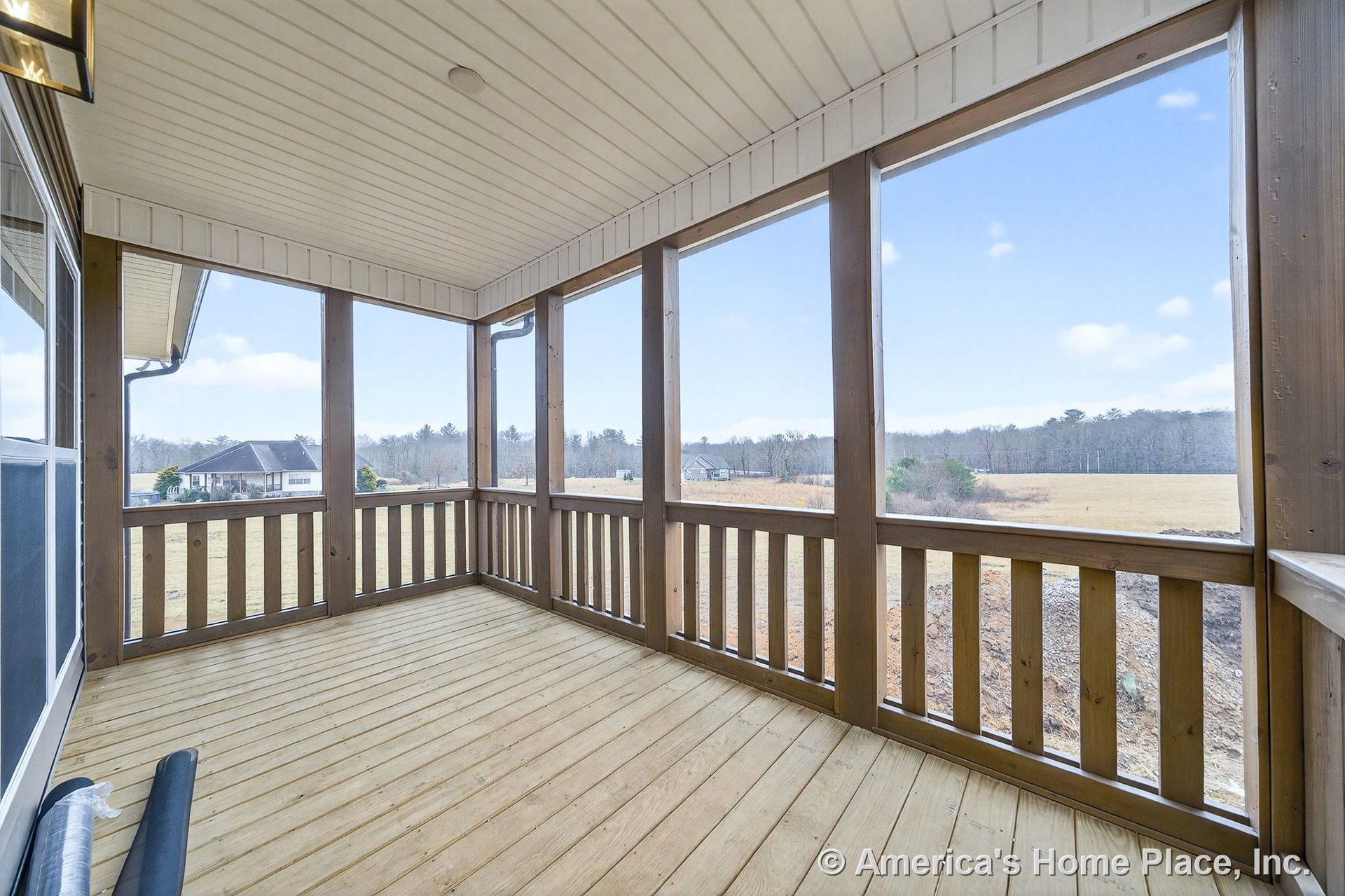 Screened-in porch featuring wood plank flooring, matching wood railing, covered ceiling with built-in lighting fixture, and exterior trim details.