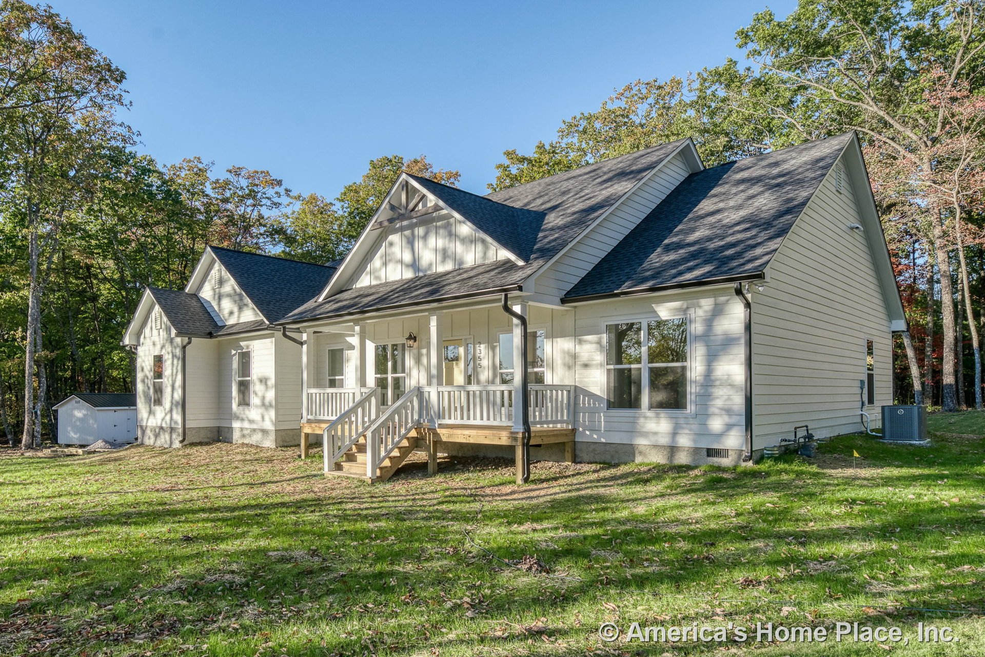 Covered front porch with white railings, white horizontal siding, black shingle roof, large double windows, detailed exterior trim, front entry steps, and prominent gable accents.