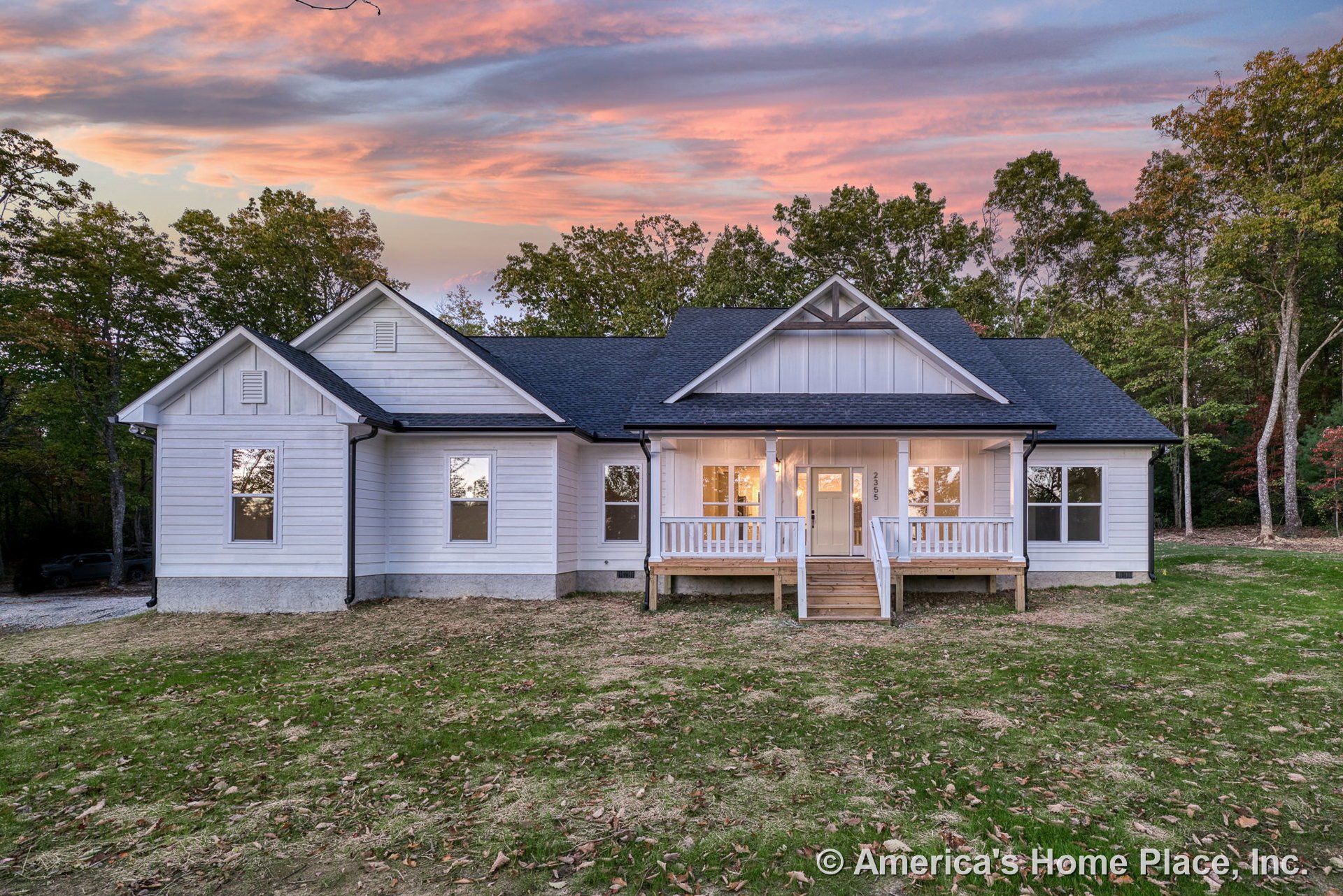 White horizontal siding exterior with multiple gabled rooflines, covered front porch, double front entry steps, black shingle roof, and several windows with contrasting trim.