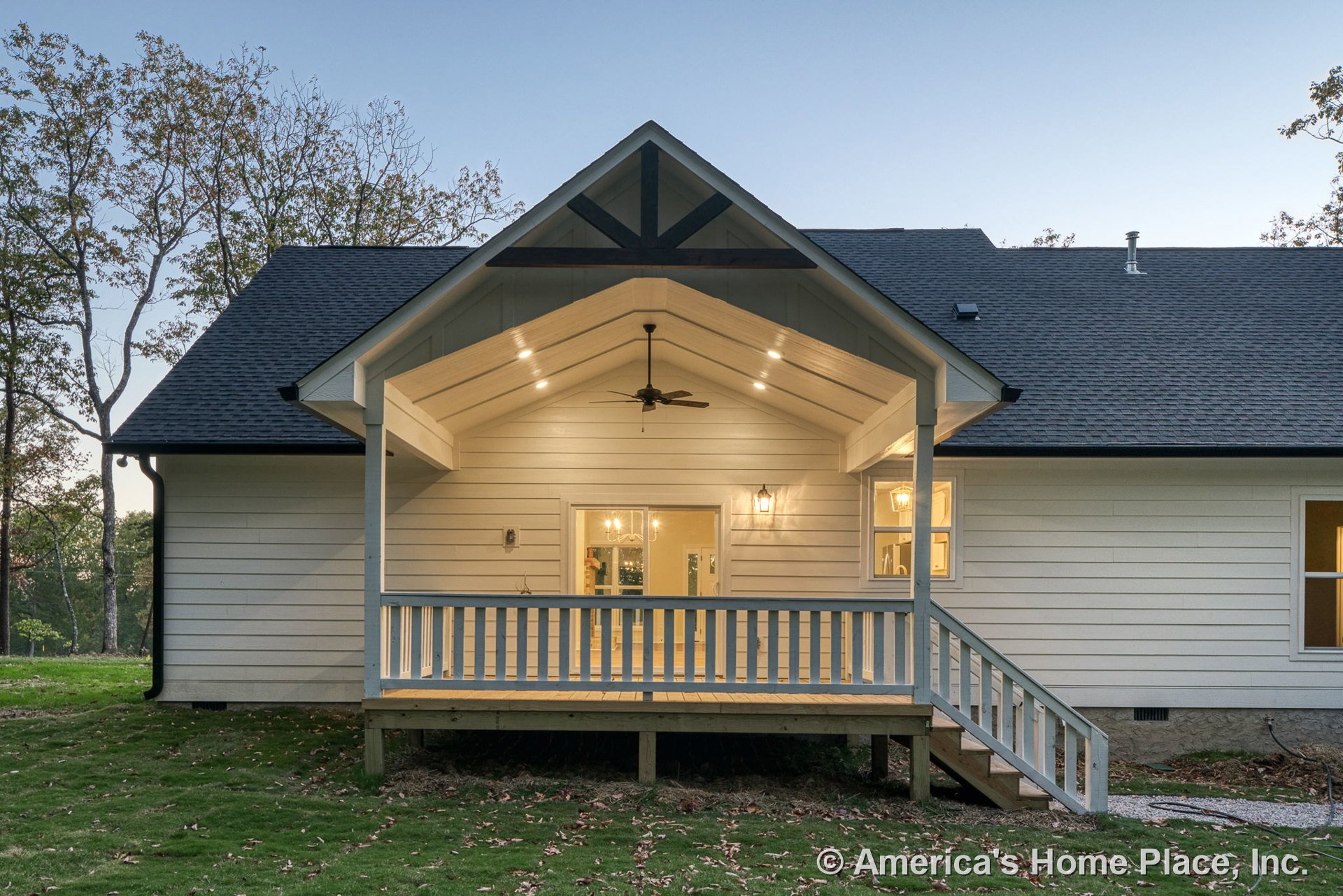 Covered back porch with vaulted ceiling, recessed lighting, ceiling fan, horizontal lap siding, wood railing, exterior wall lantern, steps, windows, and back entry door with trim.