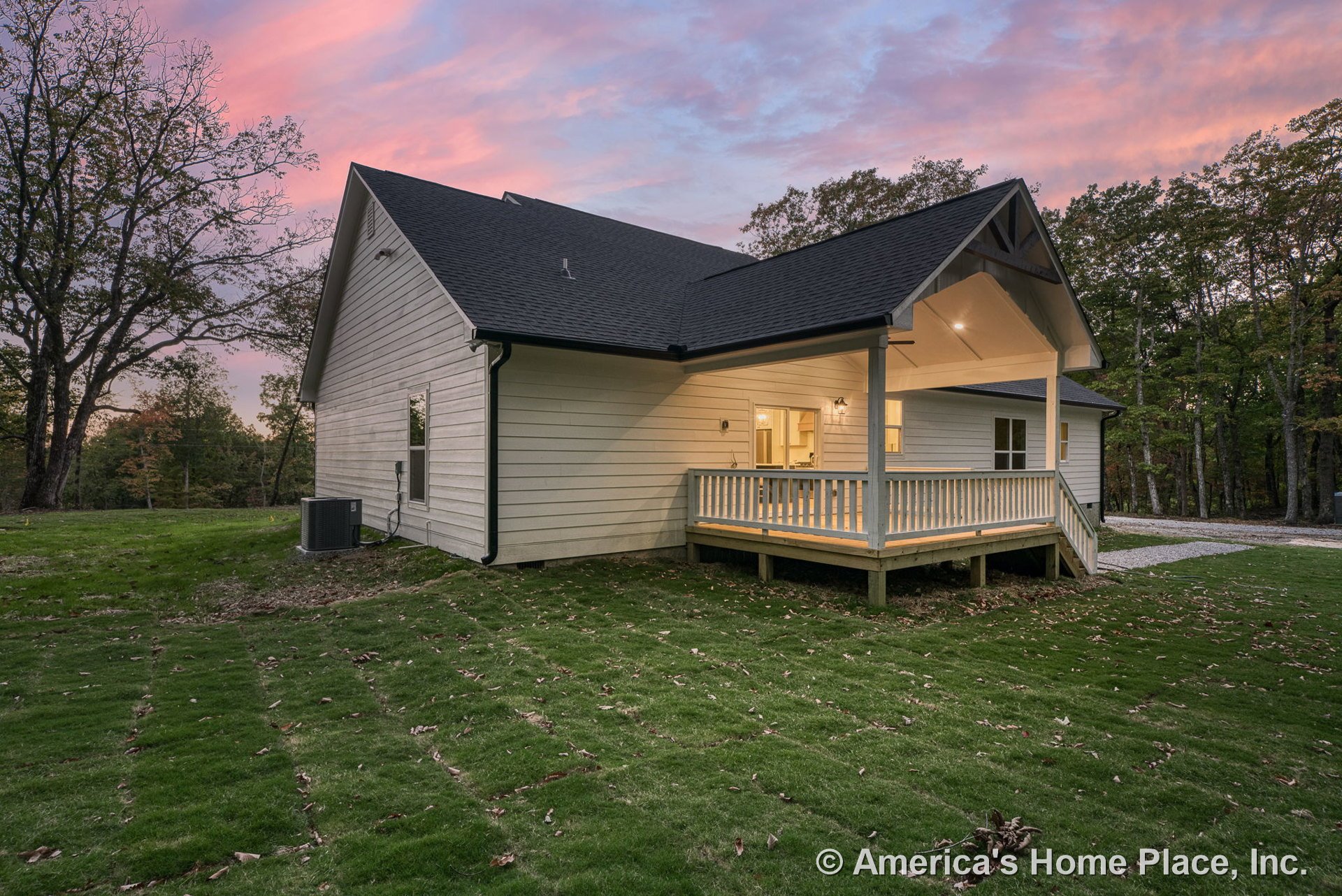 Covered back porch with wood railing, exterior siding, shingle roof, integrated lighting fixtures, newly laid sod in backyard, steps leading to porch, windows and door with trim