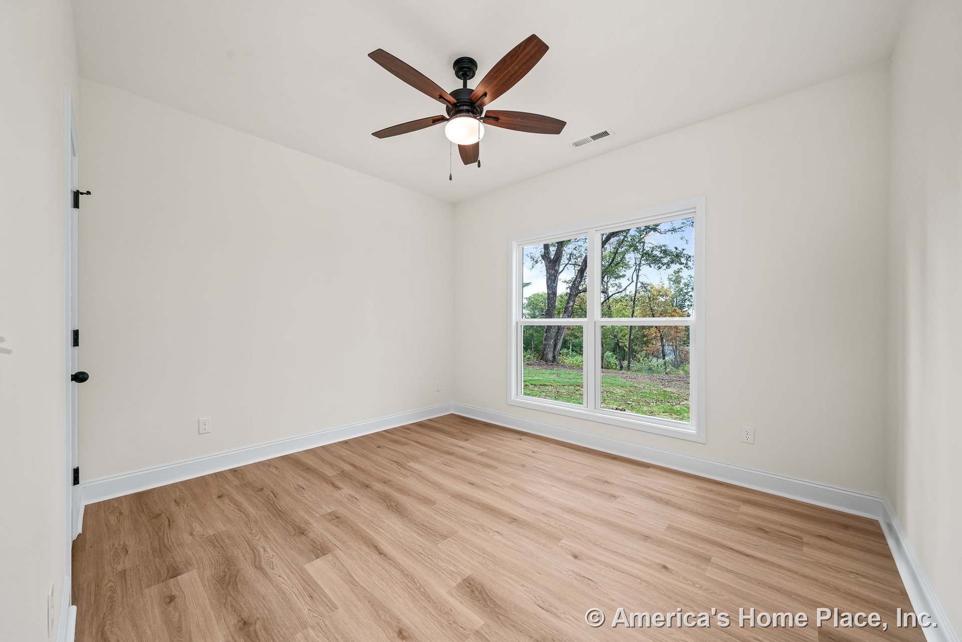Bedroom with light wood plank flooring, white baseboard trim, large double window providing natural light, ceiling fan with integrated light fixture, neutral wall color, and single