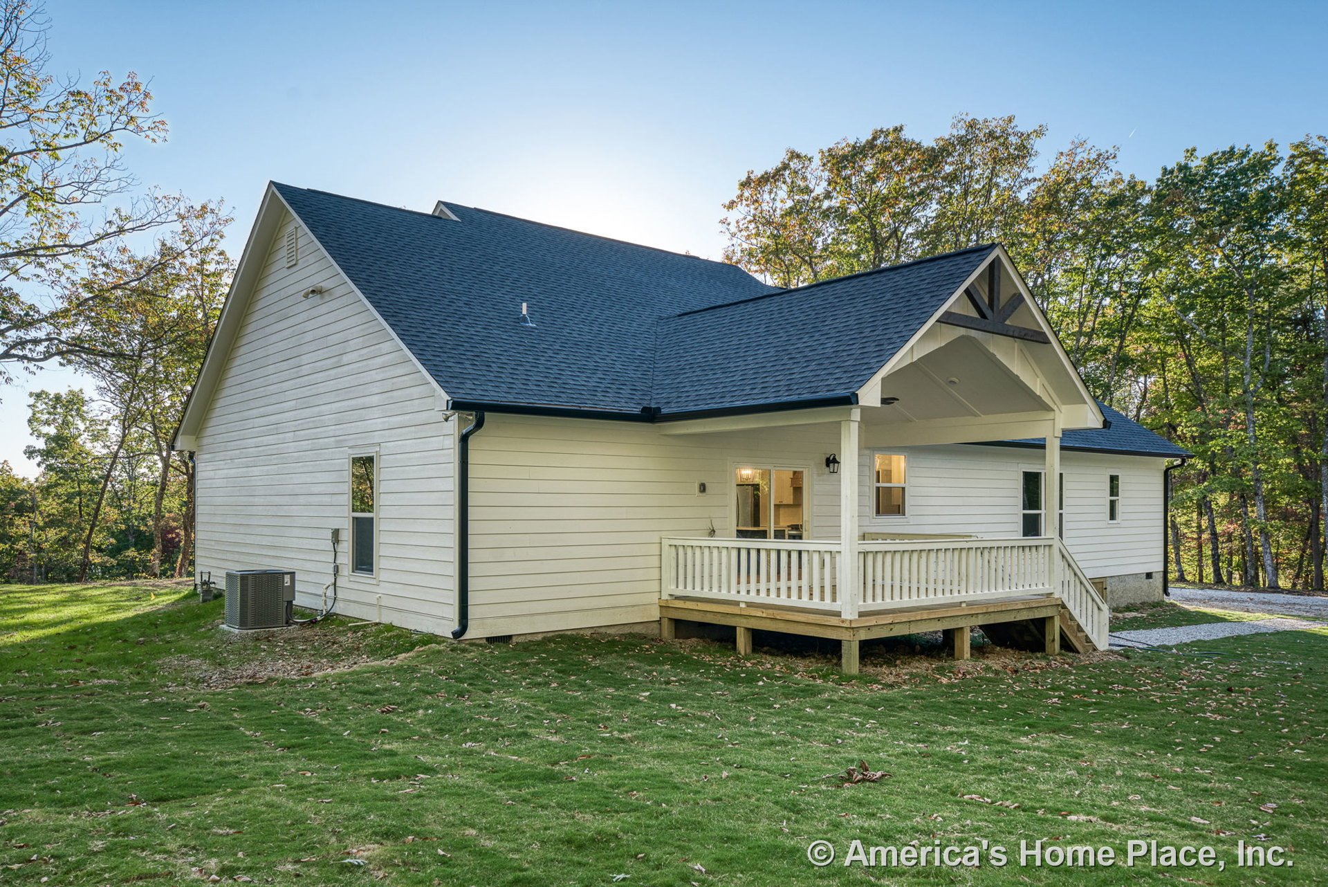 Covered rear porch with gable roof, white horizontal lap siding, wooden porch railing, exterior windows, black shingle roof, outdoor lighting fixture, white trim, steps leading to