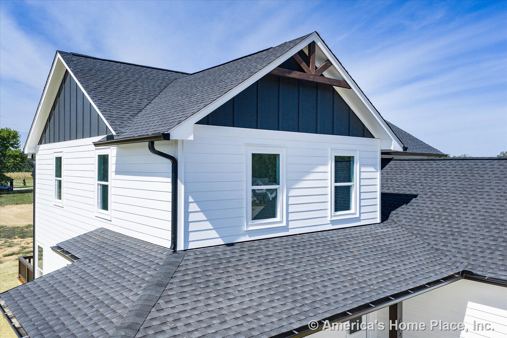 White horizontal lap siding and black vertical accent siding with architectural asphalt shingles, double-hung windows, exposed gable truss, and contrasting trim on a modern