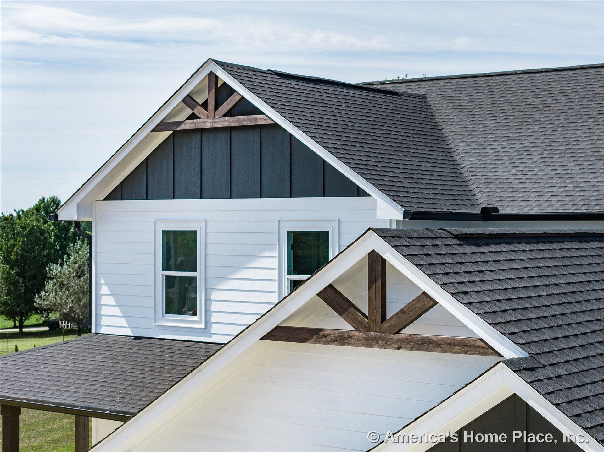 White horizontal siding with dark vertical accent panels, double-pane windows, decorative gable trusses, asphalt shingle roofing, and contrasting trim details.