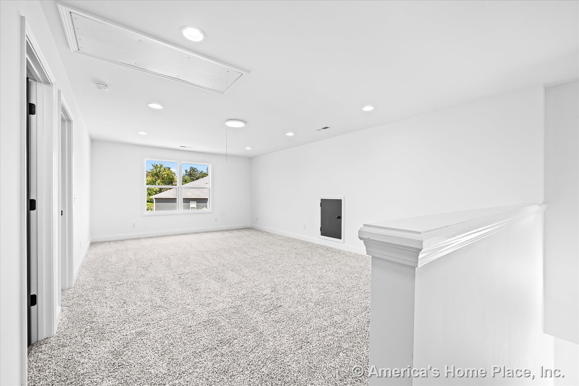 Upstairs bonus room with plush carpet flooring, recessed ceiling lights, large double window with white trim, baseboard molding, attic access panel, painted stair railing, and