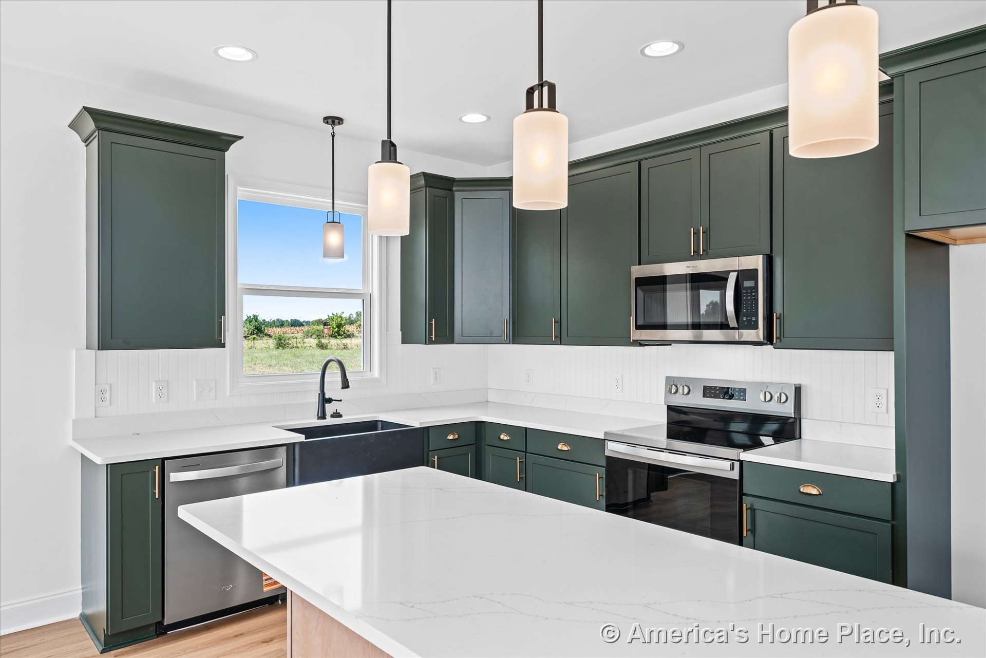 Dark green upper and lower kitchen cabinets with white quartz countertops, built-in stainless steel microwave and electric range, farmhouse-style black sink, white beadboard