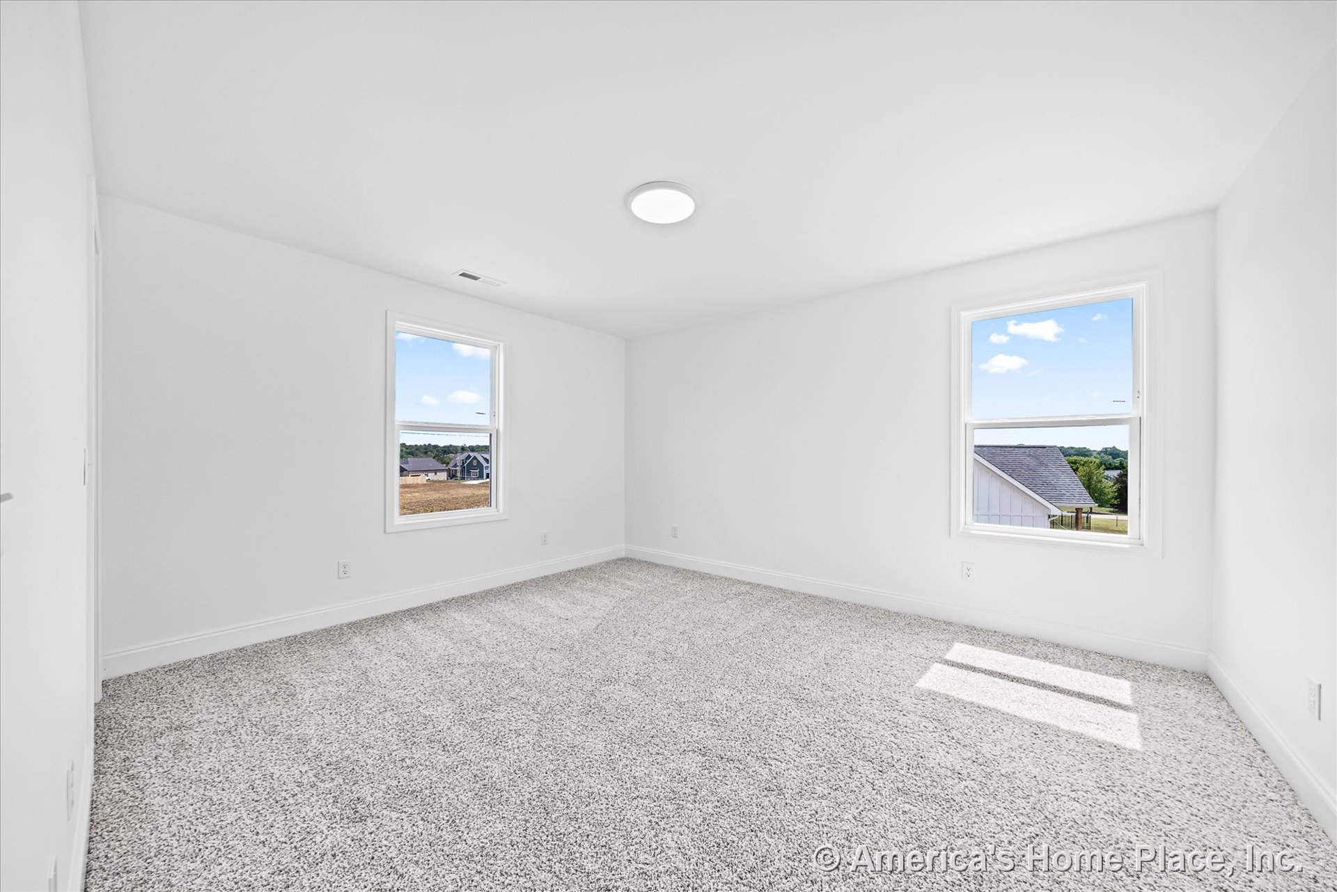 Bedroom with plush carpet flooring, two large windows framed by white baseboard trim and window casing, flush ceiling light, and neutral white walls for a minimalist, modern