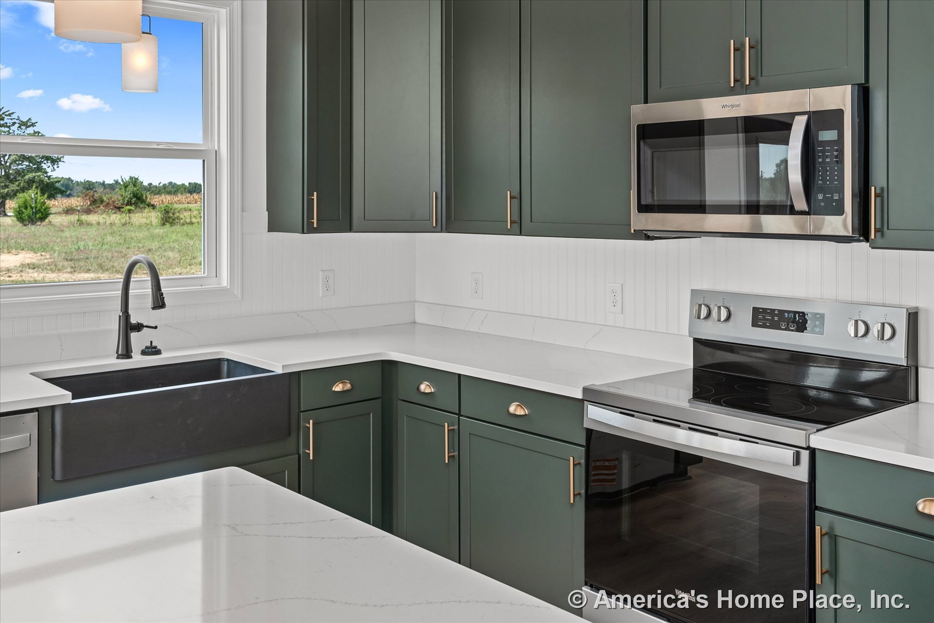 Green shaker kitchen cabinets with brushed gold hardware, white quartz countertops, farmhouse-style black sink with matte black faucet, white beadboard backsplash, stainless steel