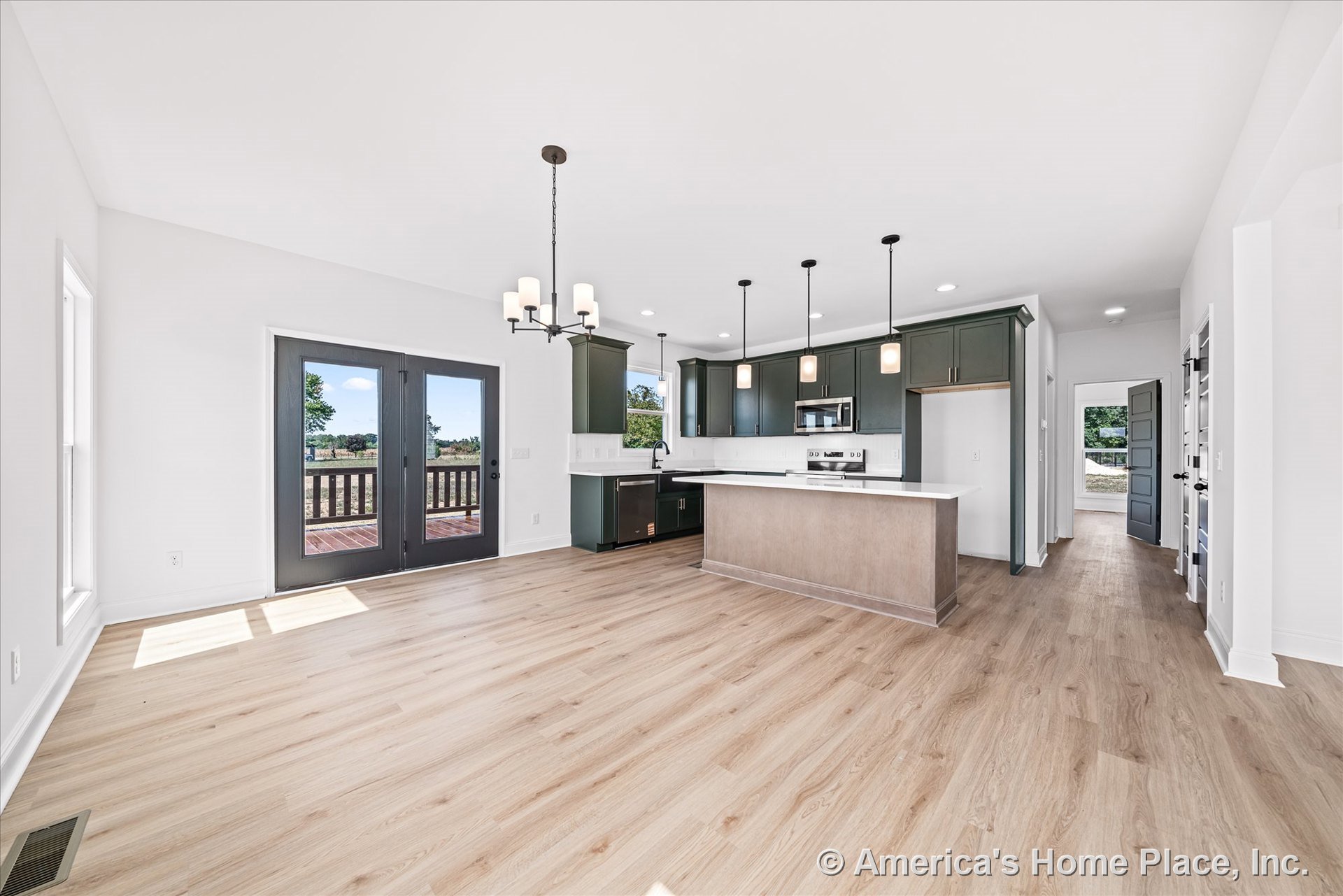 Open kitchen with green cabinetry, white quartz countertops, white tile backsplash, and pendant lights above a storage-equipped island; built-in stainless appliances, light wood