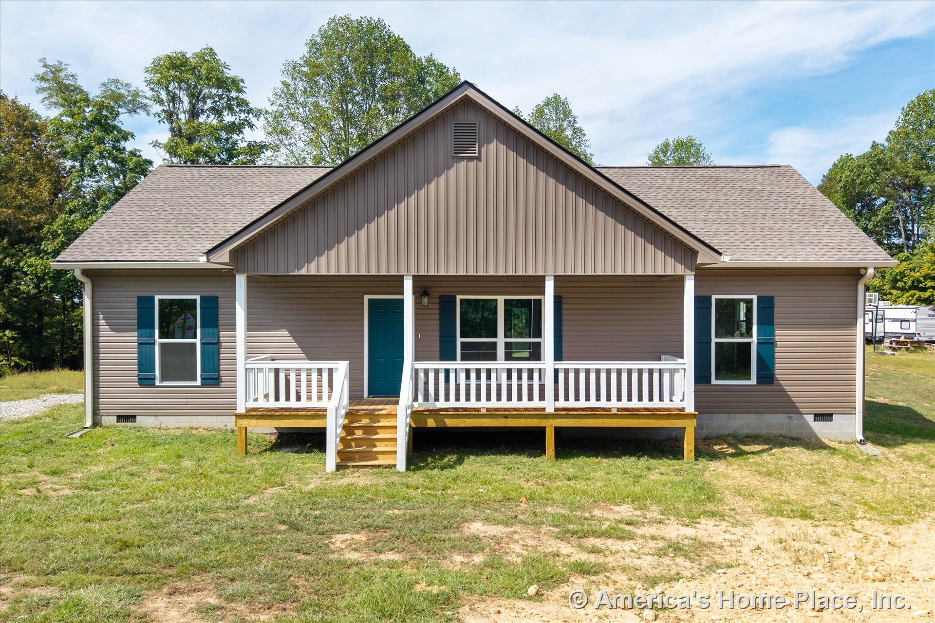 Covered front porch with white railings, gabled shingle roof, vinyl siding exterior, blue front door, double-hung windows with shutters, wooden porch steps, and decorative trim