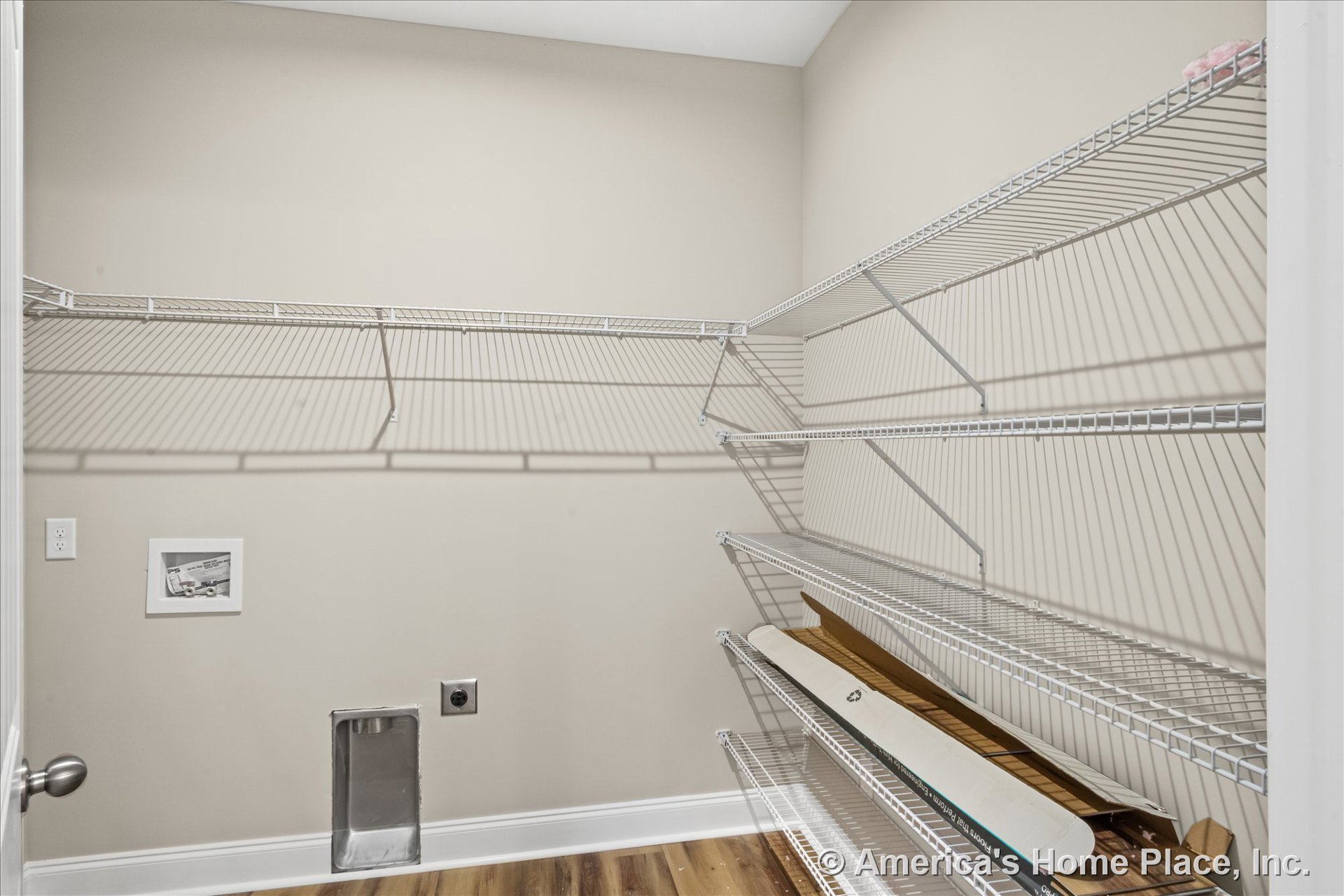 Laundry room with wire shelving on walls, utility outlet and vent, wood-look vinyl flooring, neutral painted walls, white baseboard trim, and recessed ceiling lighting.