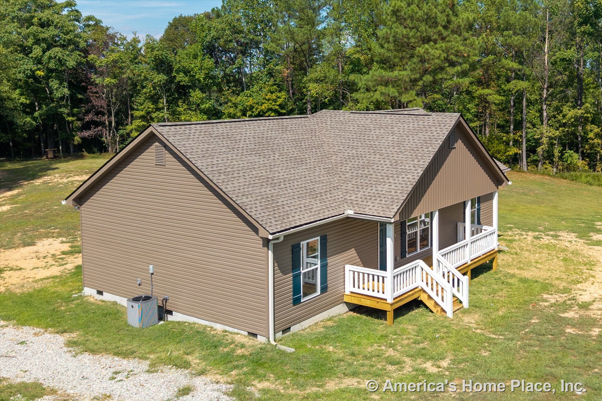 Tan vinyl siding exterior with gable roof clad in asphalt shingles, covered front porch featuring white railings and steps, double-hung windows, exterior HVAC unit, and white trim