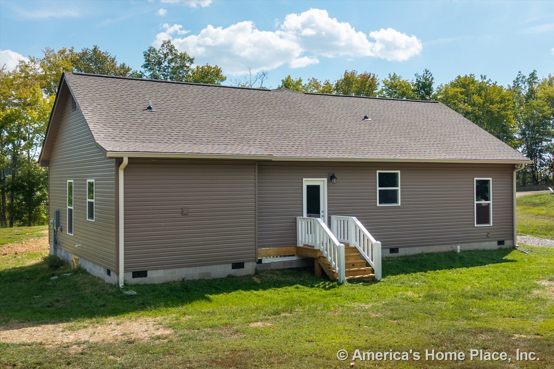 Tan vinyl siding exterior with asphalt shingle roof, small entry porch featuring white railings and steps, single exterior door, double-hung windows, concrete block foundation