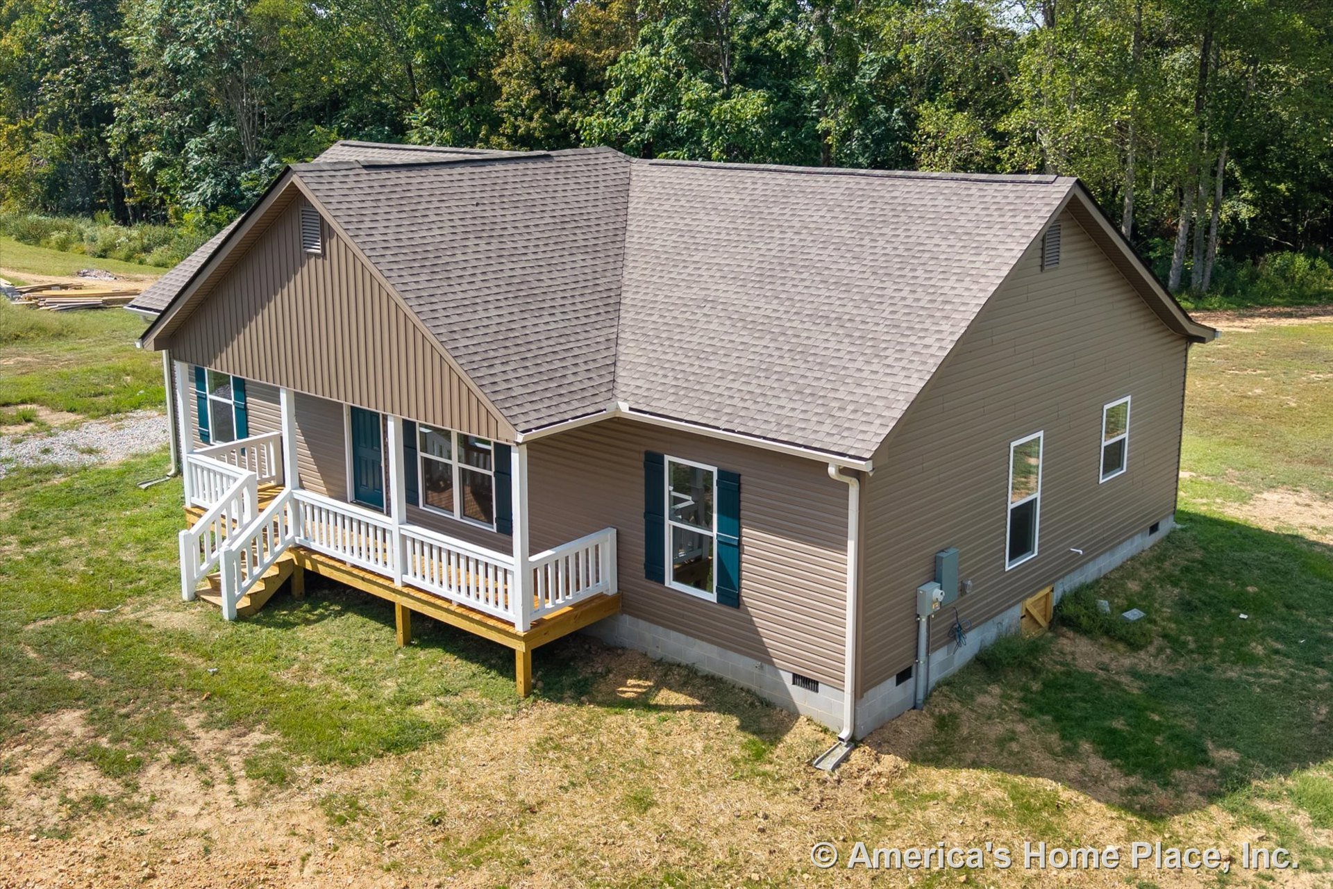 Tan vinyl siding exterior with gable roof clad in asphalt shingles, covered front porch featuring white railings and entry steps, double-hung windows with shutters, visible