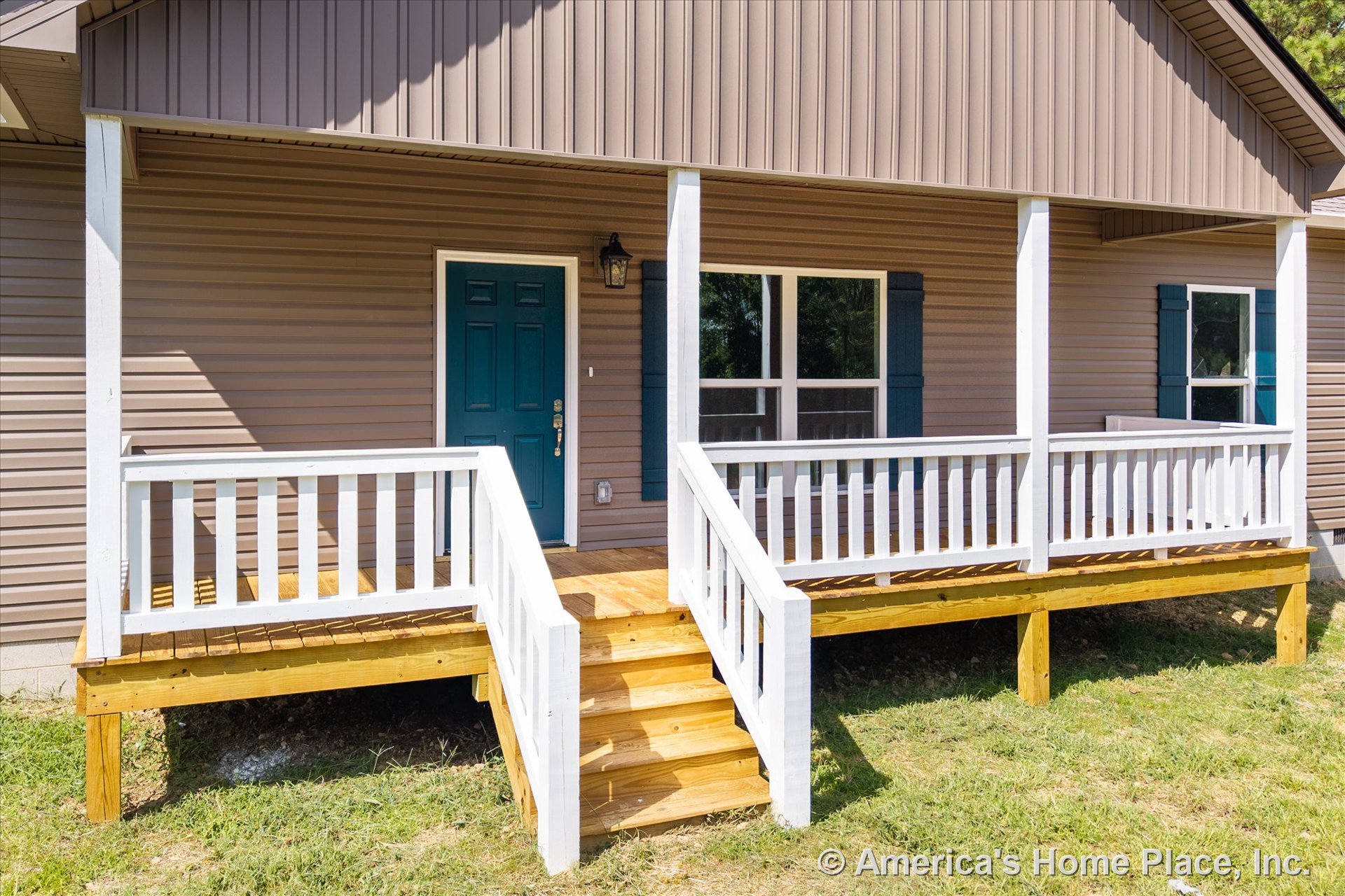 Covered front porch with white railings, wood decking, and wooden steps; blue front door; vinyl siding exterior; white porch columns; double window with shutters; exterior