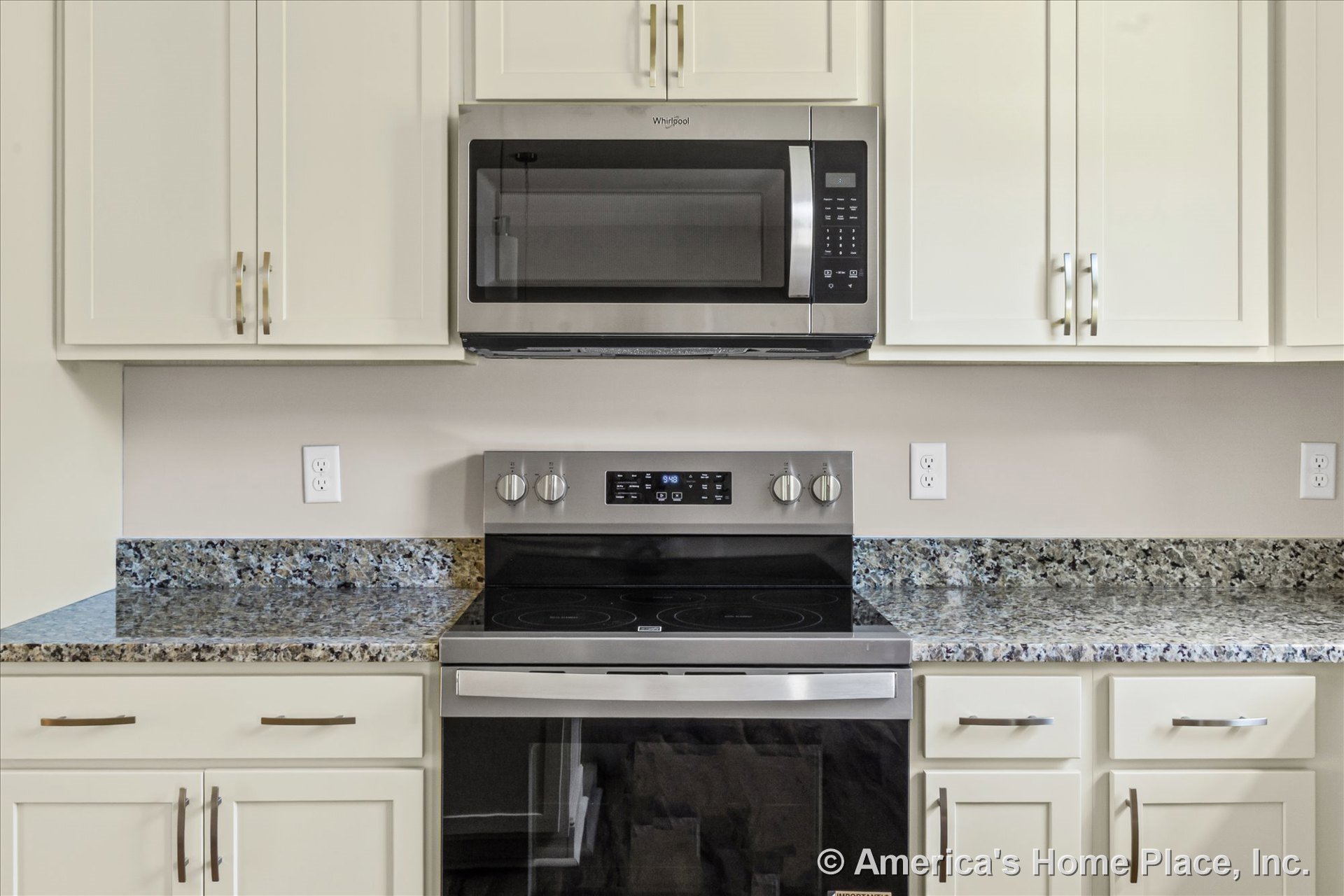 White shaker cabinets with modern hardware, granite countertop and matching backsplash, stainless steel electric range with built-in microwave above, multiple electrical outlets