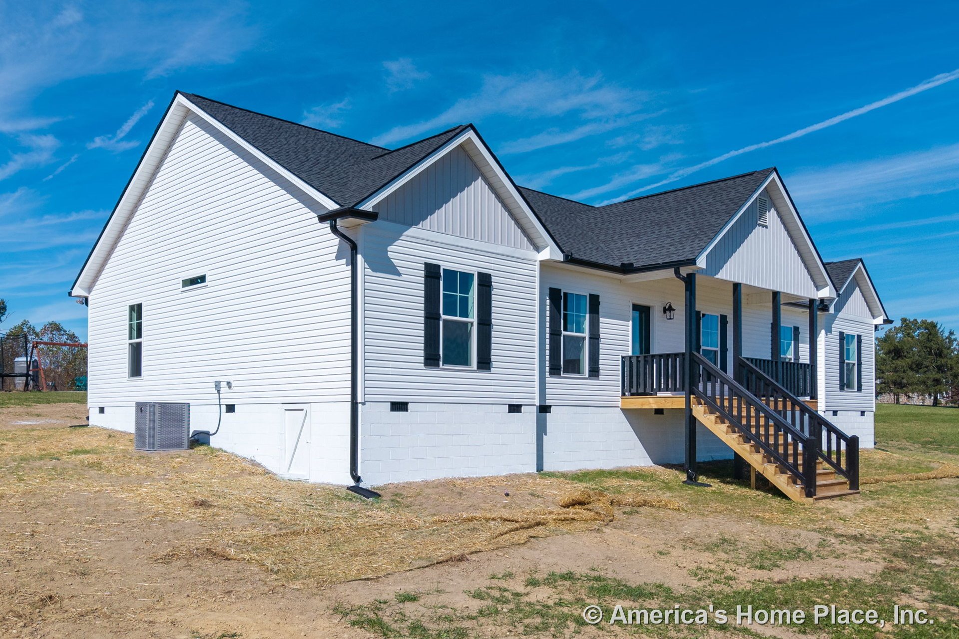 White vinyl siding exterior with black window shutters and trim, gabled roof, covered front porch featuring wooden steps and railing, foundation visible, exterior HVAC unit, and