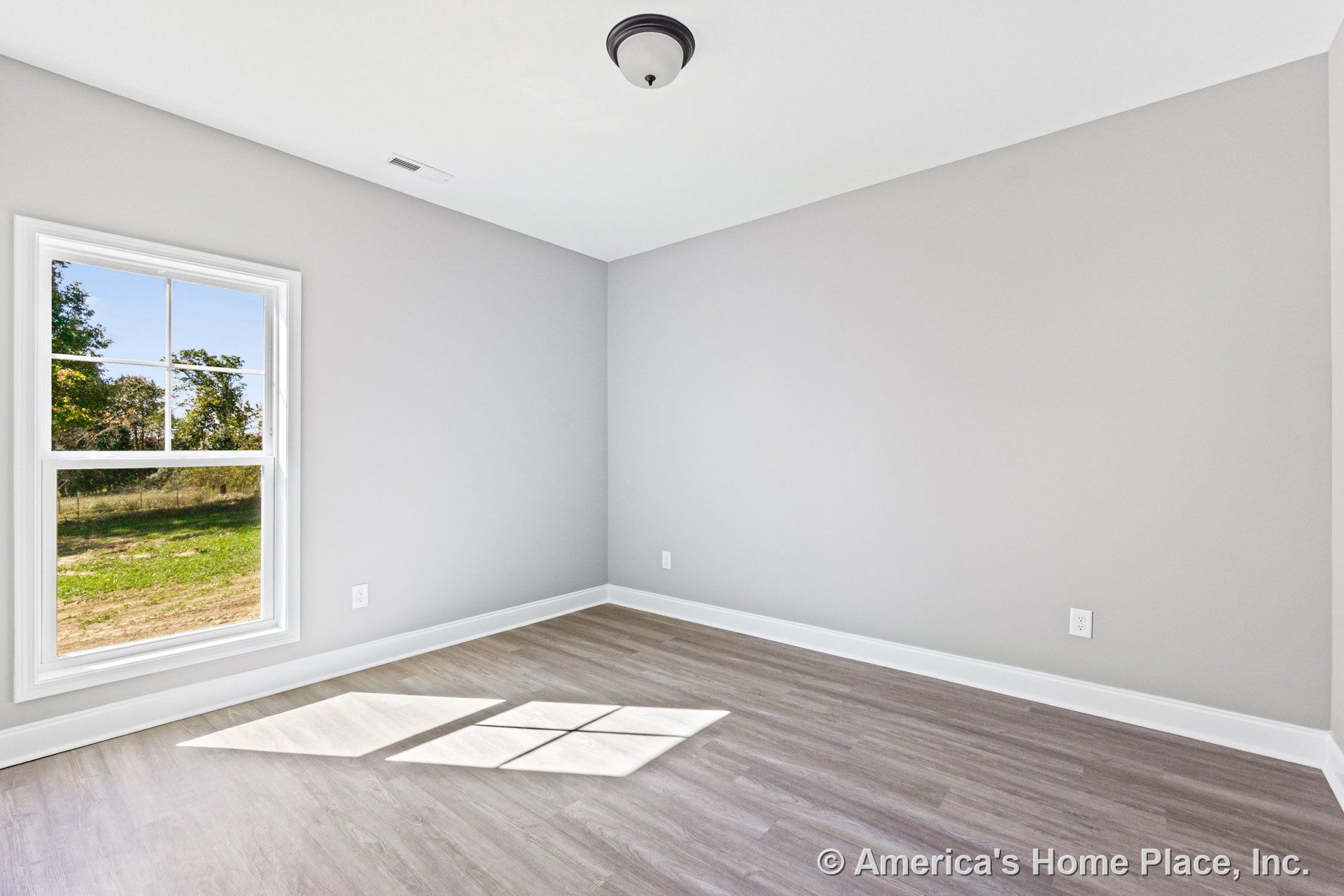 Bedroom with light gray walls, double-hung window allowing natural light, wood-look vinyl plank flooring, white baseboard trim, flush mount ceiling light, and rectangular layout