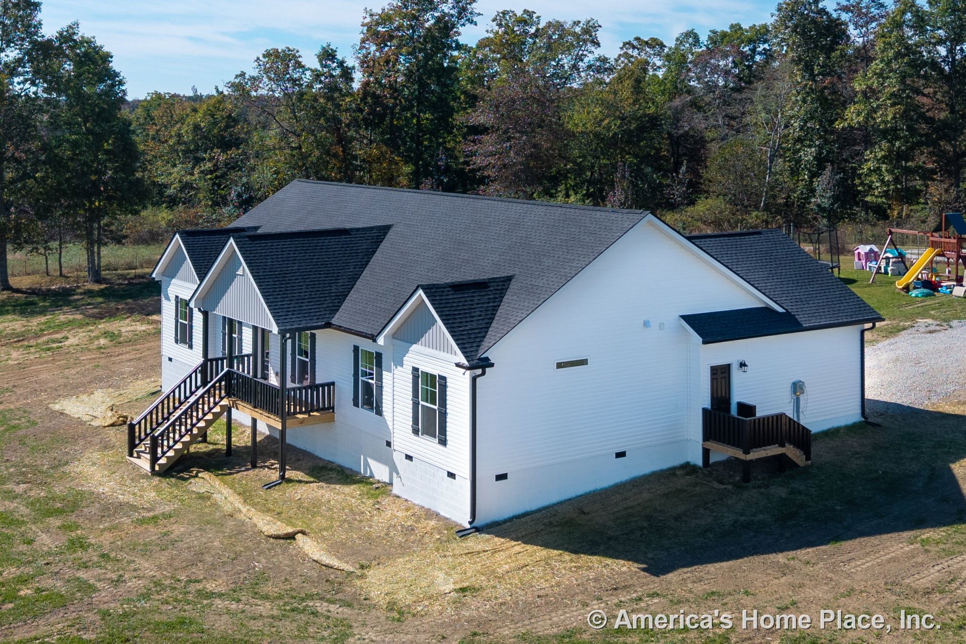 White siding exterior with black shingle roof, covered front porch featuring black railing and trim, multiple double-hung windows, raised foundation with entry stairs, and