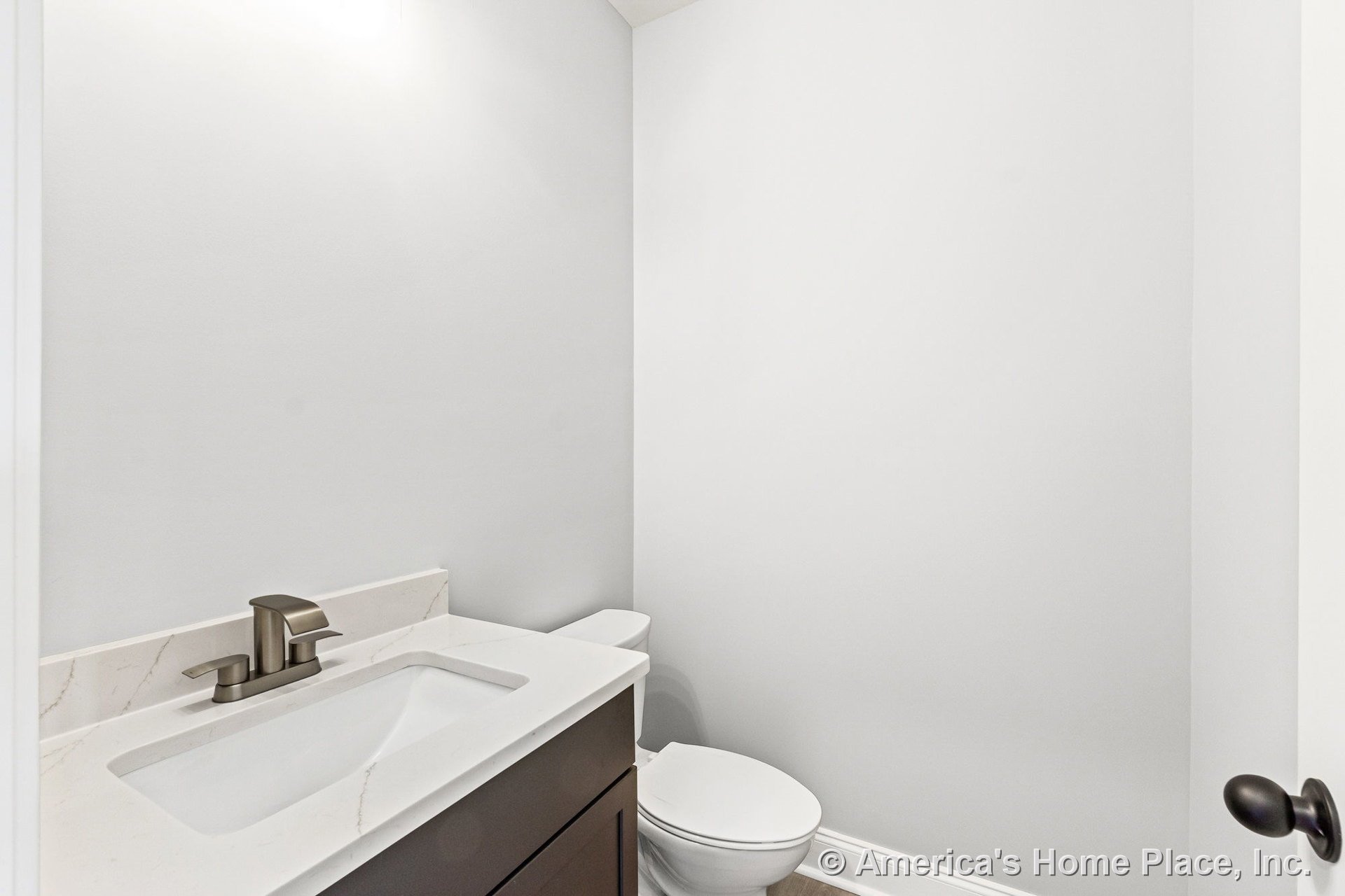 Modern small bathroom with dark wood vanity, white quartz countertop, undermount sink, single lever faucet, white toilet, light gray walls, and baseboard trim.