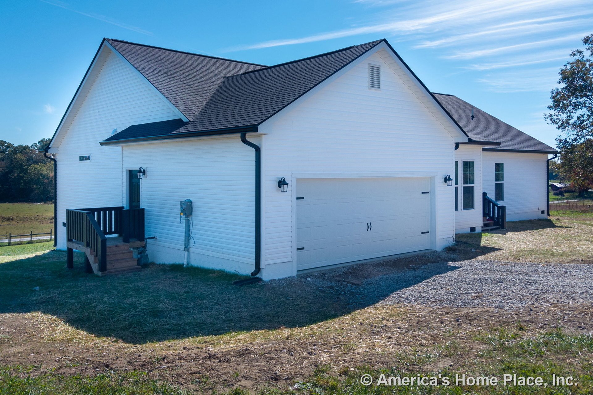 White vinyl siding exterior with black roof shingles, gutters, and trim; attached two-car garage; small entry porch with stairs; wall-mounted exterior lights; windows and entry