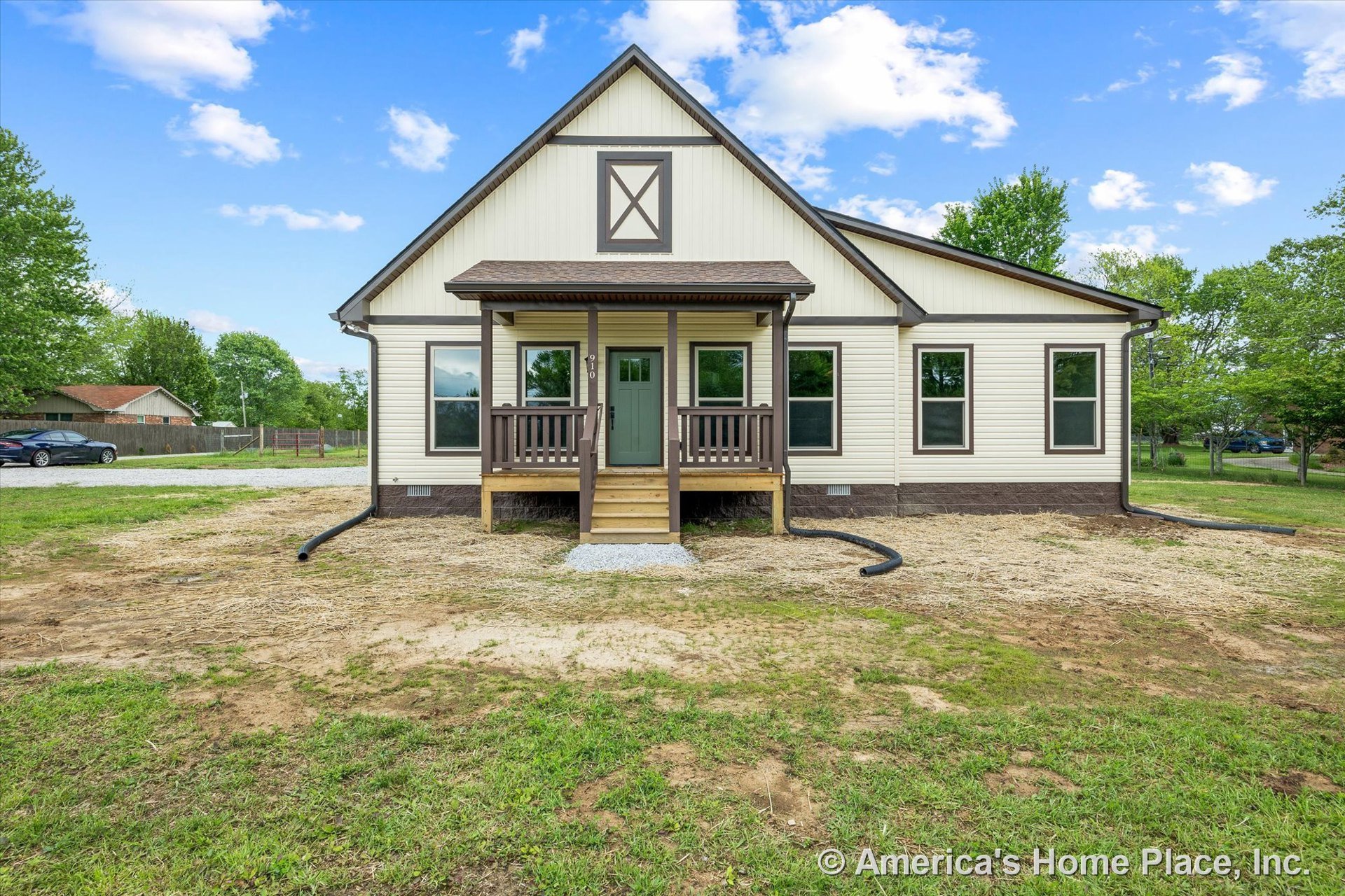 Covered front porch with wood railings and steps, multiple large windows, gabled roof, contrasting trim, and vinyl siding exterior surrounding the front entry.