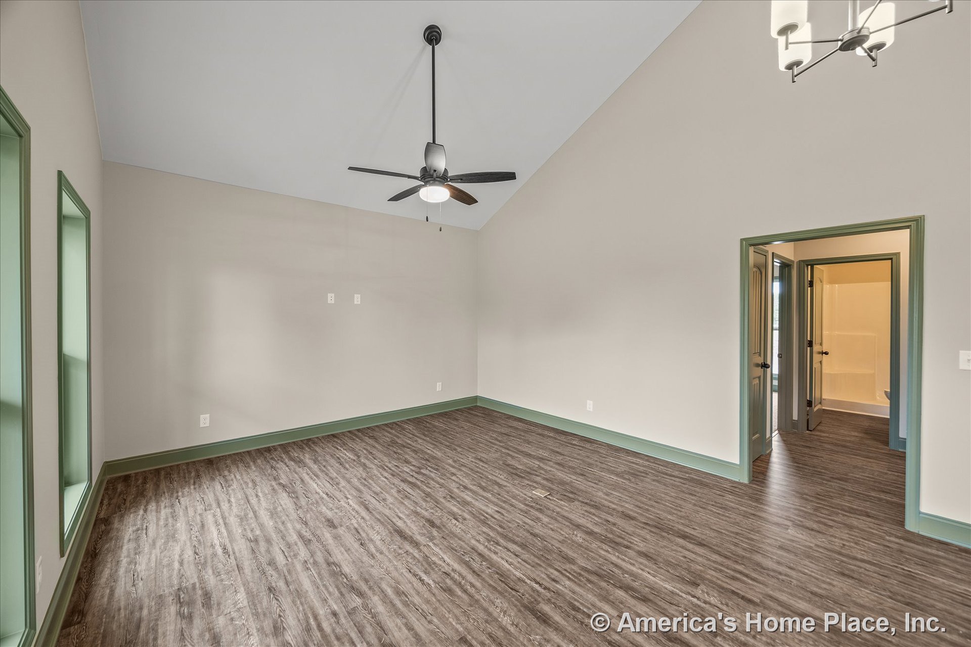 Vaulted ceiling with ceiling fan and built-in overhead lighting, wood-look vinyl flooring, green trim framing windows, doors, and baseboards, neutral wall color, empty room