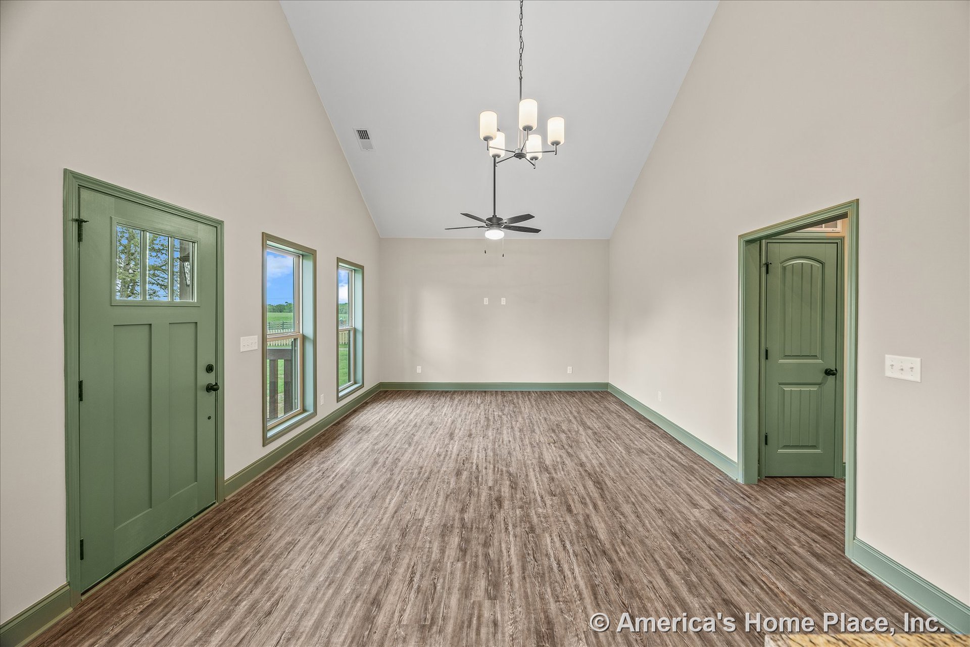 Living room with green trim, three tall windows, green entry and interior doors, wood-look vinyl plank flooring, vaulted ceiling, ceiling fan with light, chandelier, neutral wall