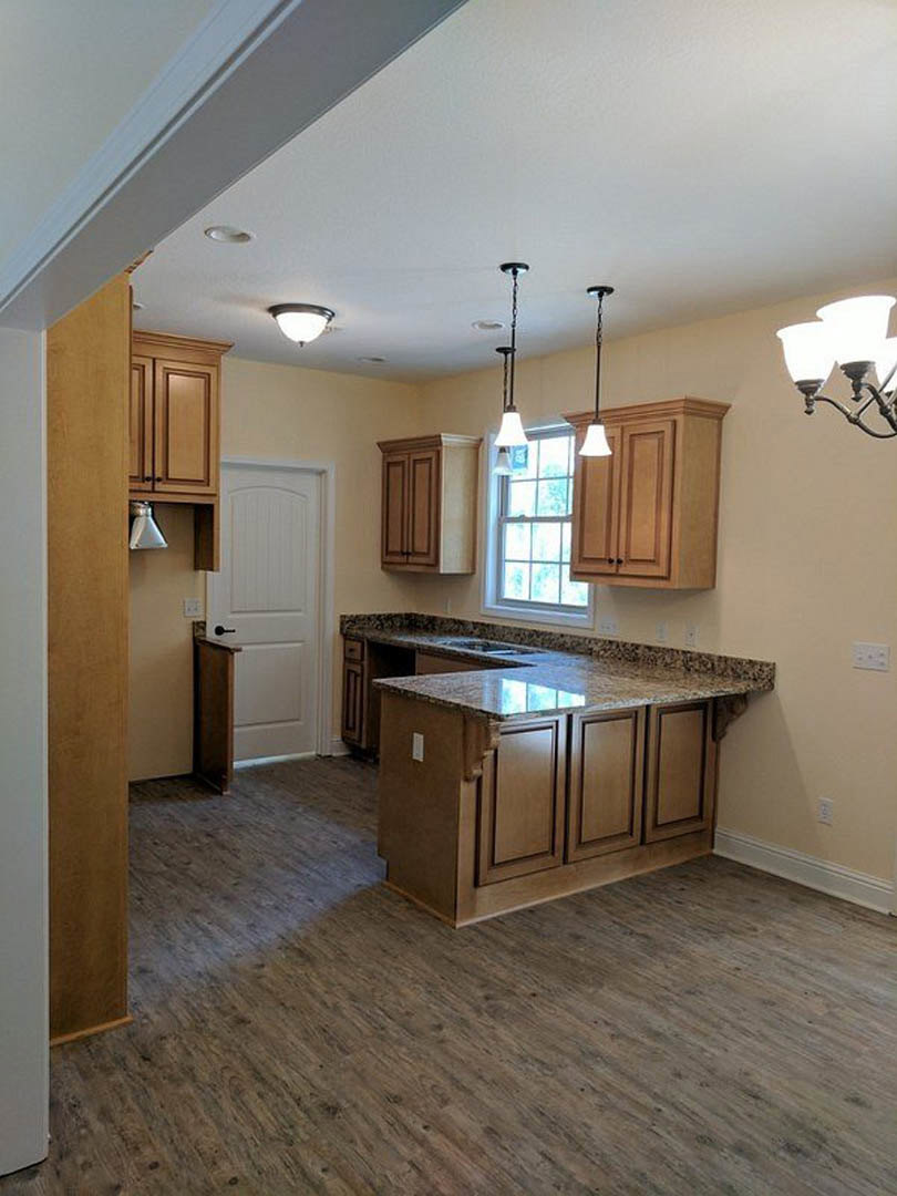 Marble kitchen countertop with wood flooring, white cabinetry, black door handle, ceiling light fixture, and tile backsplash