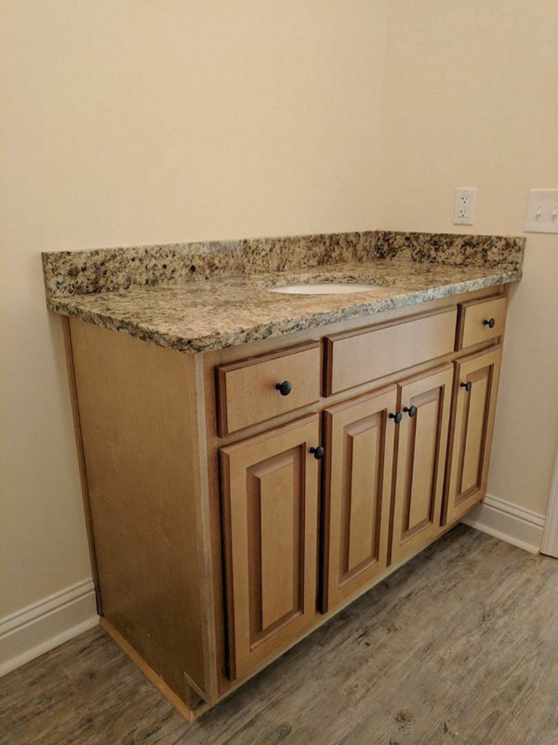 Marble bathroom countertop with undermount sink, wooden vanity drawers, and tiled backsplash