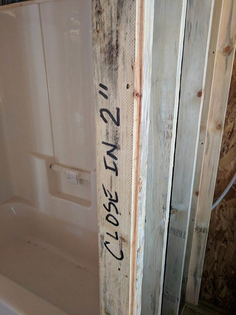 Exposed wood beam with handwritten black numbers, close-up view showing grain and texture