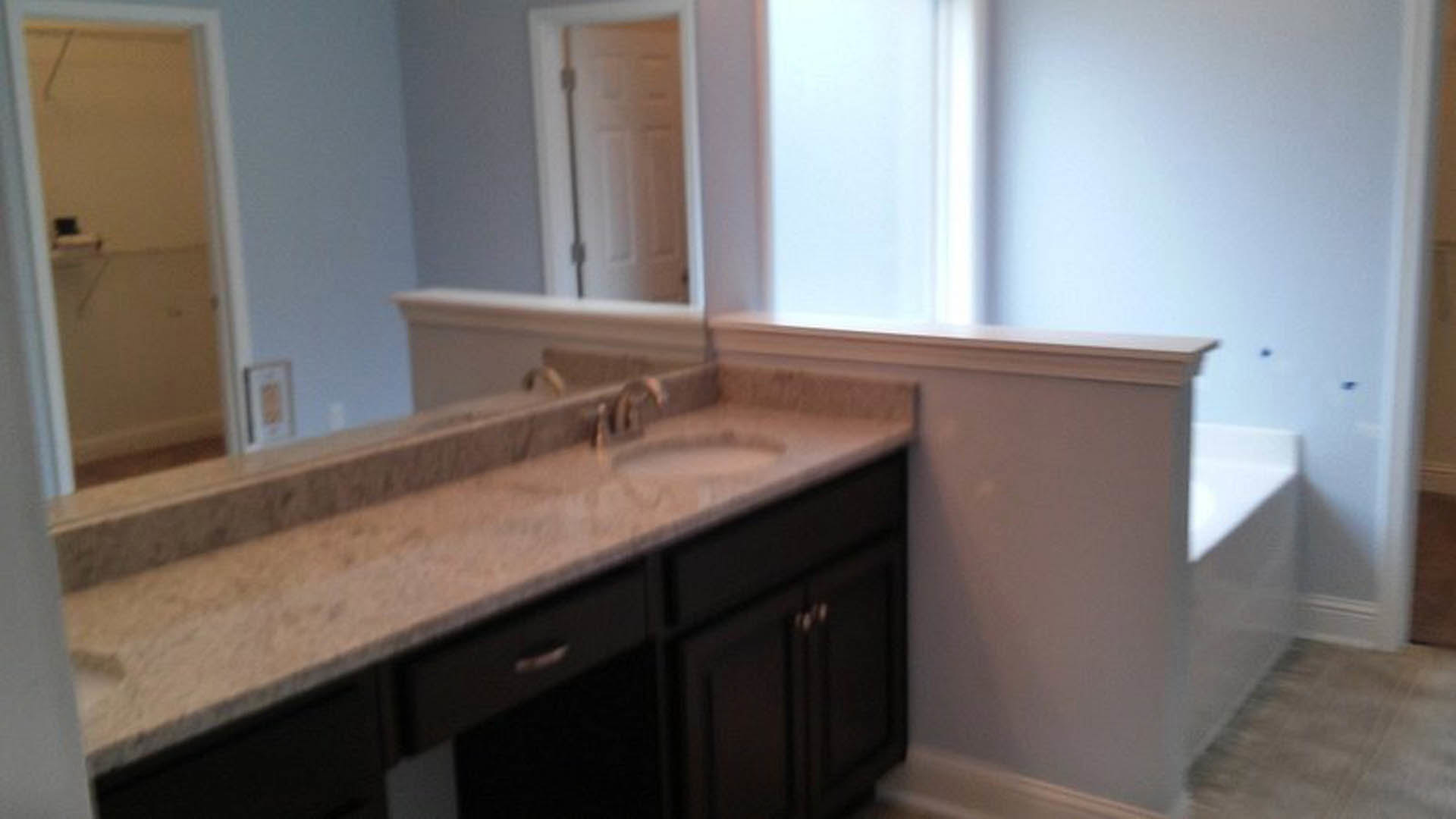 Bathroom featuring marble countertop, white cabinetry, chrome faucet, and tiled walls