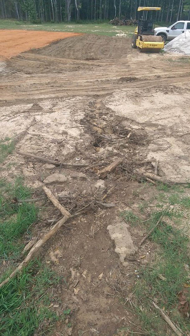 Dirt road with a large hole, white pickup truck parked nearby with driver visible, yellow vehicle with black roof, person holding red gas can beside snow pile, dense forest of