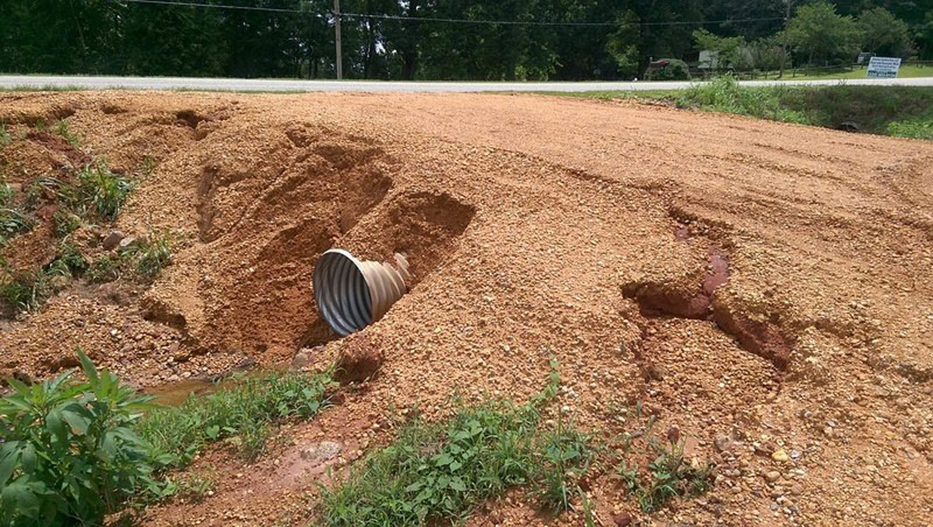 PVC pipe partially buried in loose soil near grass and tree roots