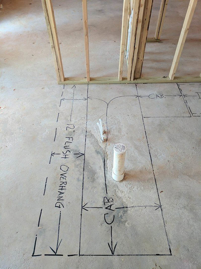 Wood-framed construction site with handwritten drawings and notes on unfinished floor, including a sketch of a car and black lettering on white surfaces