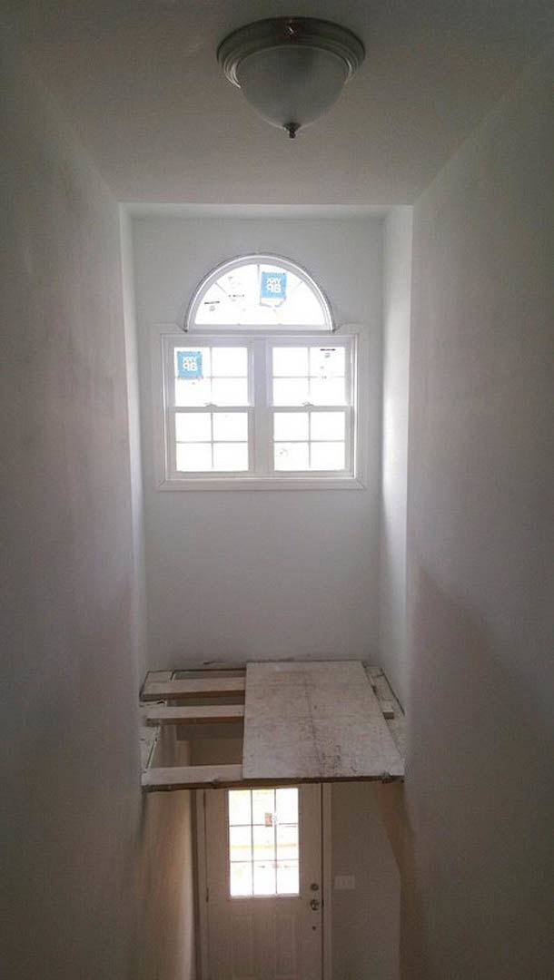 Bright room with two large windows, white door with glass insert, white tile flooring, plaster walls, and decorative molding.