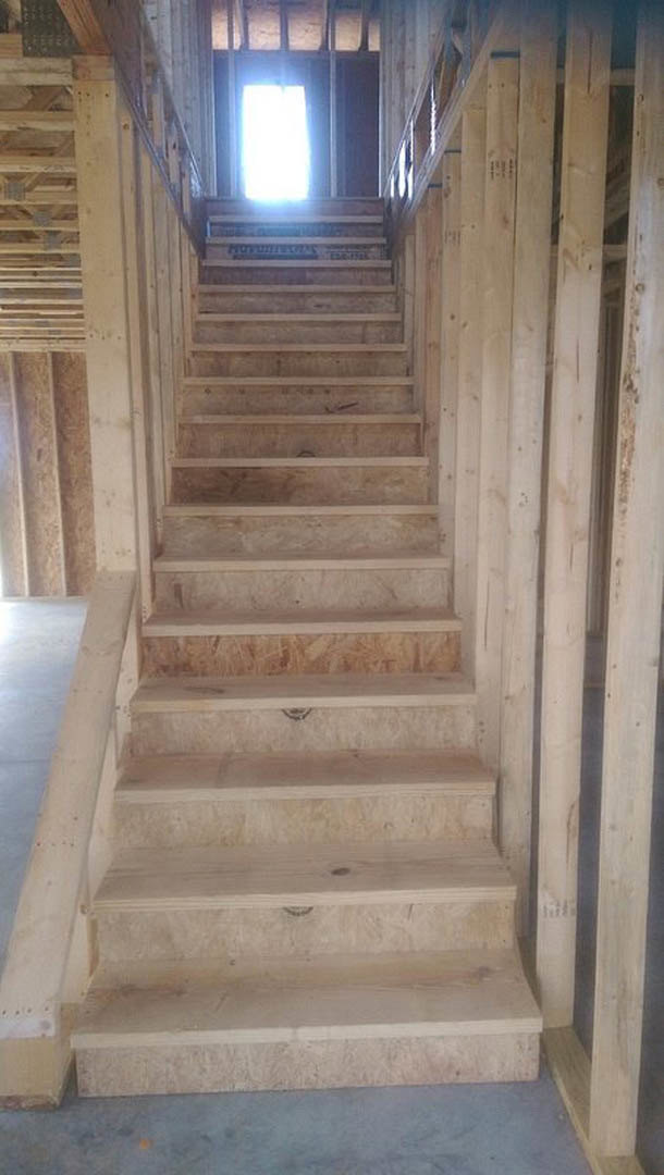 Wood plank staircase with matching handrail, white walls, and light hardwood flooring in a modern residential interior