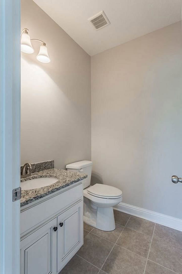 Marble bathroom countertop with undermount sink, chrome faucet, and adjacent white toilet; tile flooring and partial view of ceiling vent