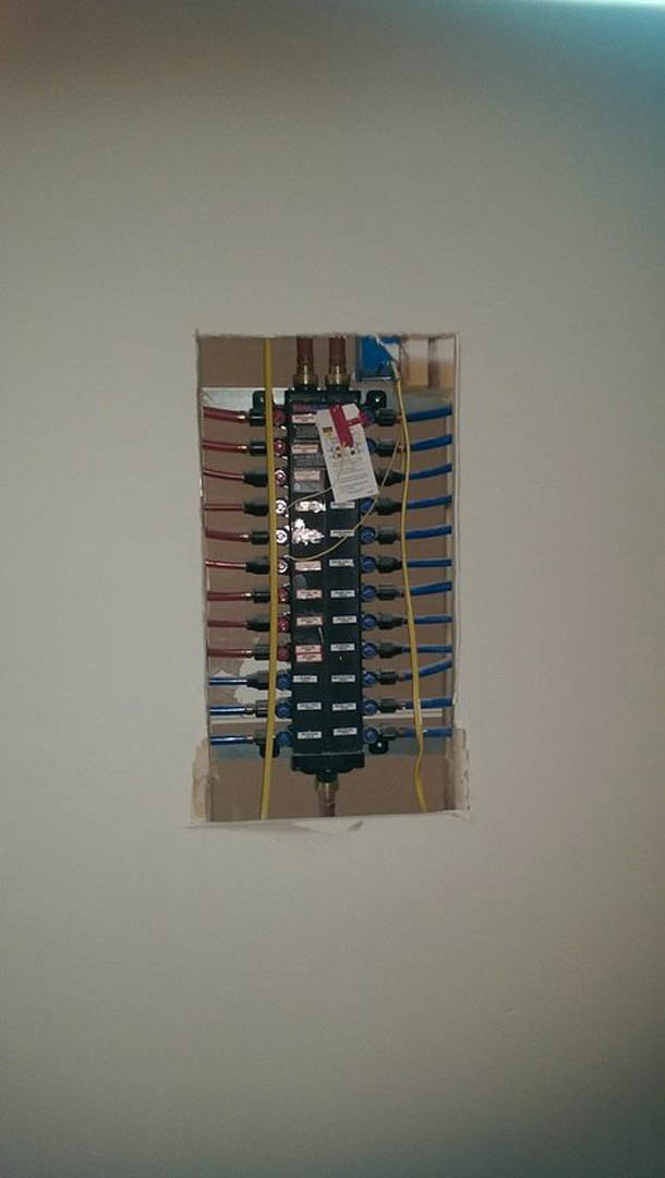 Rectangular electrical panel mounted on interior wall, filled with organized wires and cables