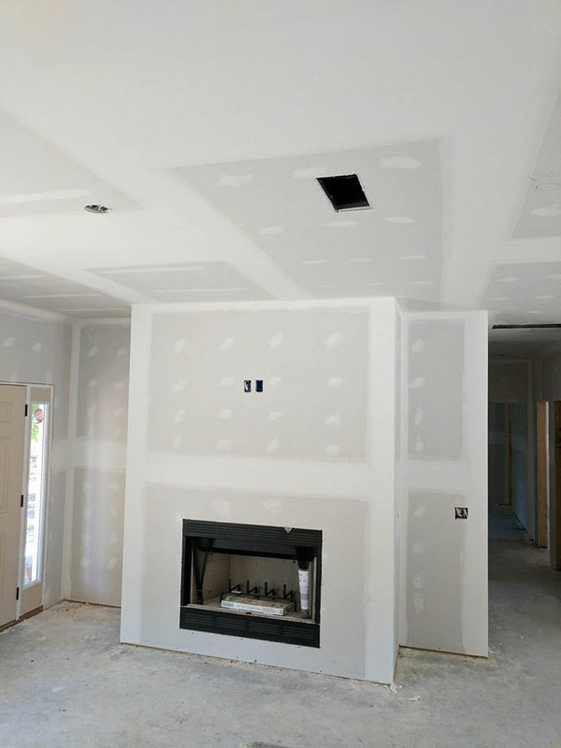 White plaster fireplace with black hearth set into a living room featuring light wood floors, white walls, and a door with a window.
