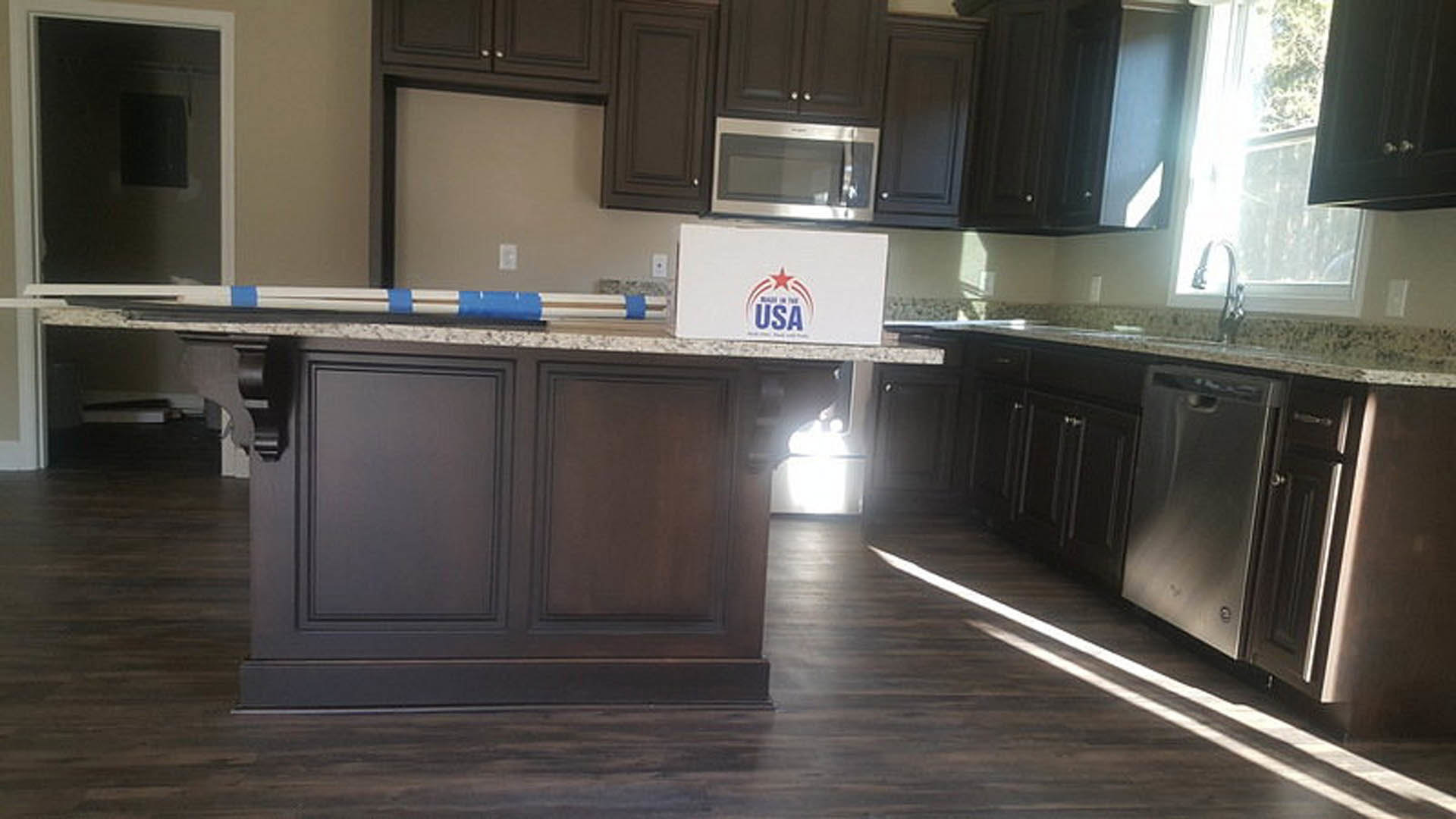 Modern kitchen with white cabinetry, quartz countertops, stainless steel sink, and a white microwave on the counter