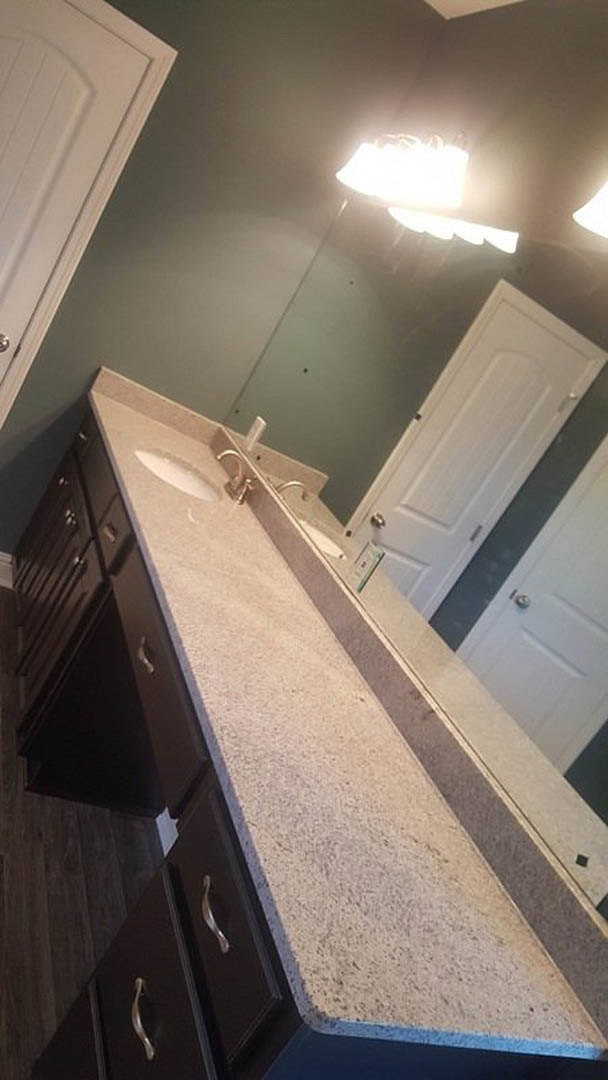 Bathroom with marble countertop, double sinks, white cabinetry, large mirror, and white door; soft lighting and neutral finishes throughout.