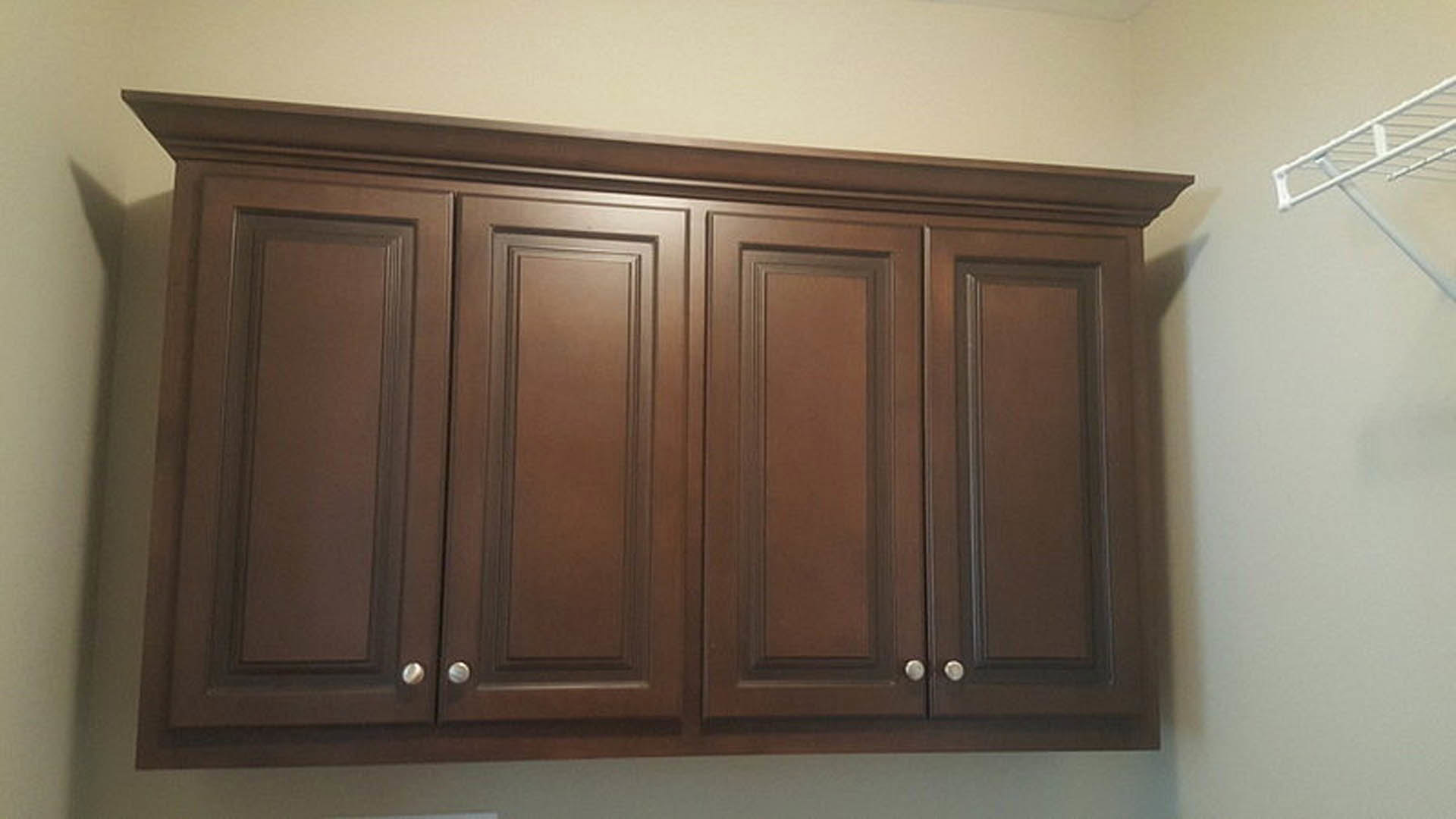 Brown wooden cabinets with silver knobs against a white wall in a residential kitchen interior