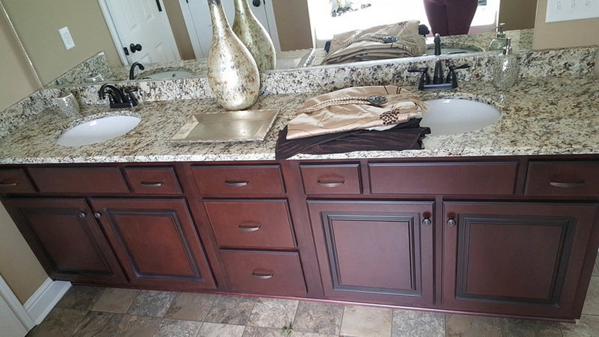 Bathroom with marble countertops, white cabinetry, chrome faucet, and decorative vase on the vanity
