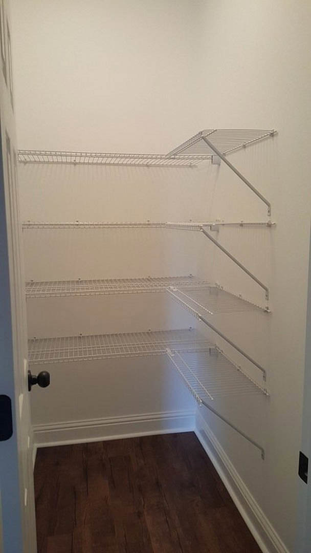 White closet interior with metal shelving, dark wood flooring, and white trim