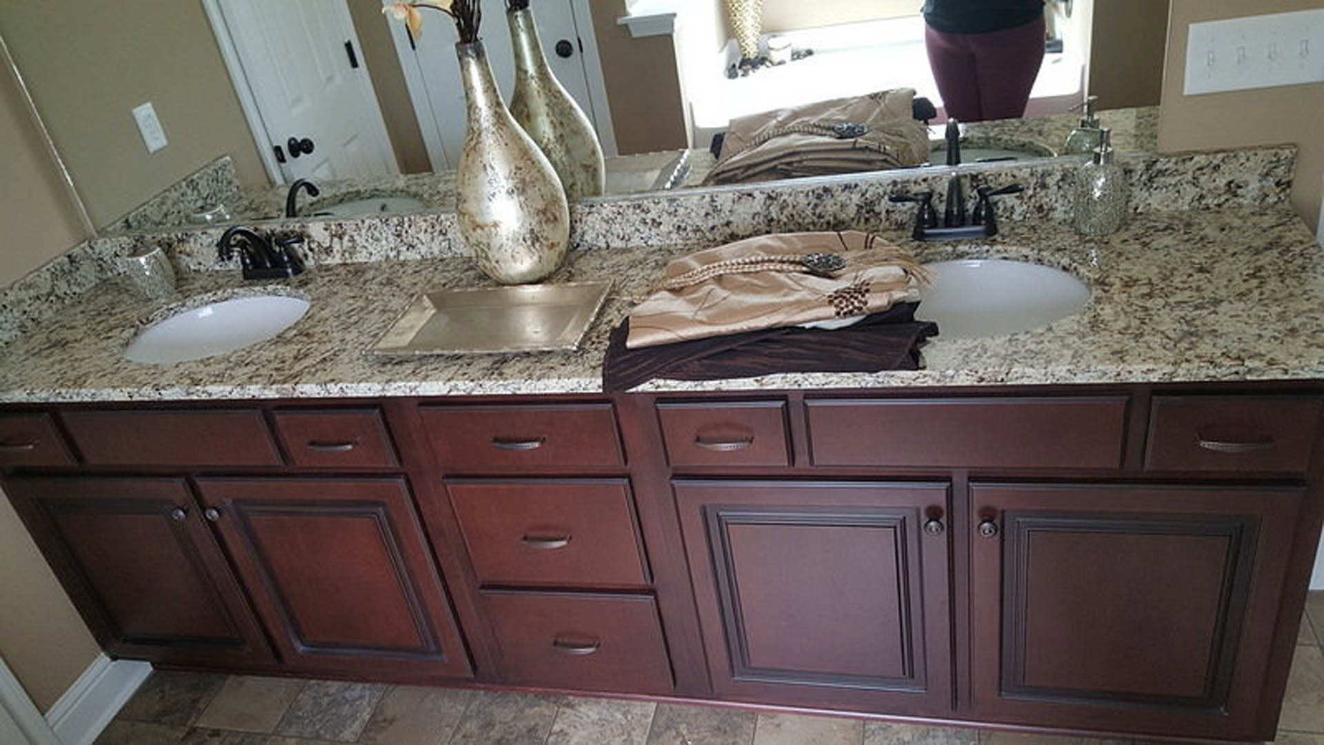 Bathroom with marble countertops, white cabinetry, chrome faucet, and decorative vases on the vanity