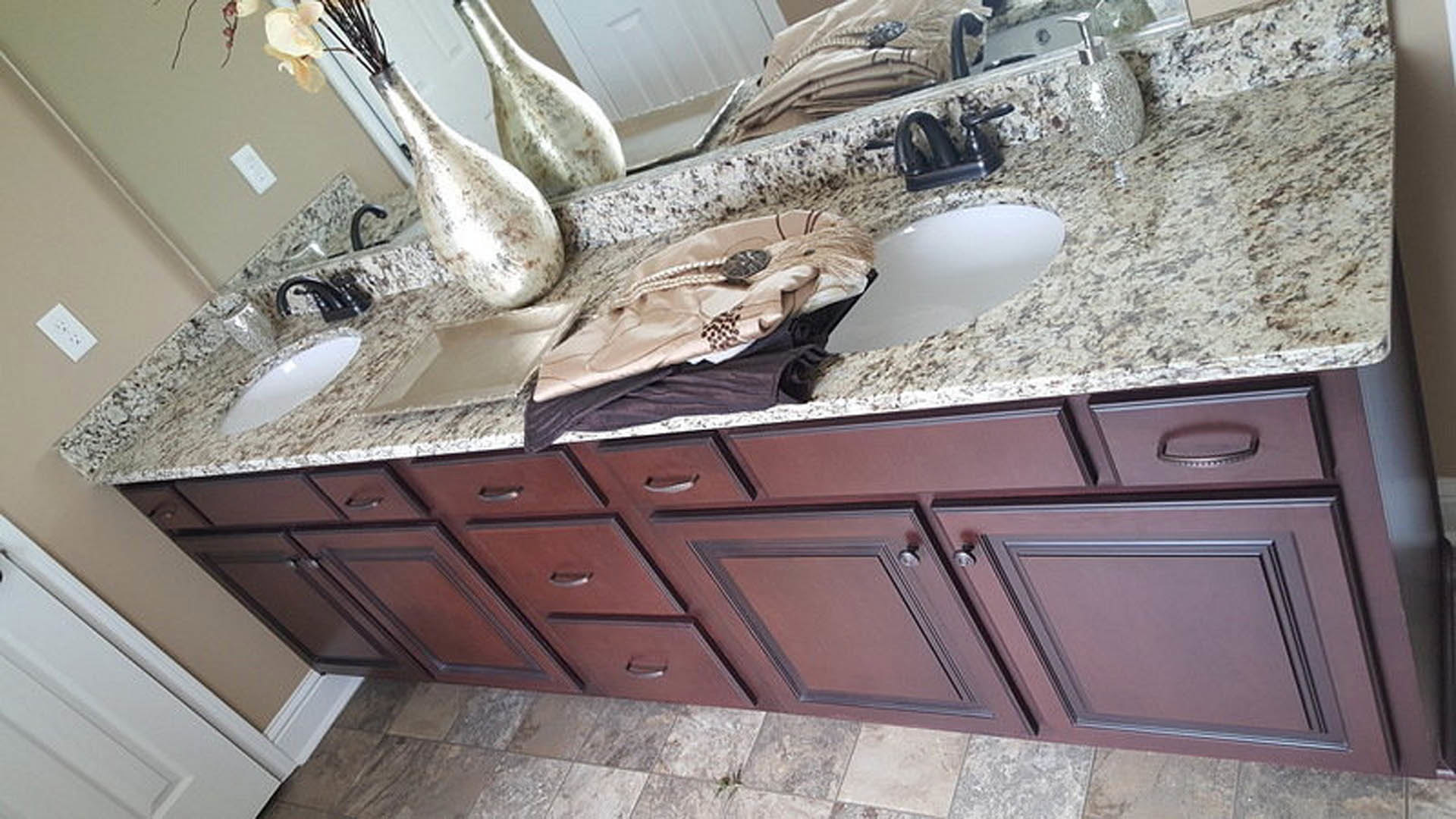 Bathroom featuring marble countertop, undermount sink, chrome faucet, light-colored tile backsplash, and dark wood cabinetry