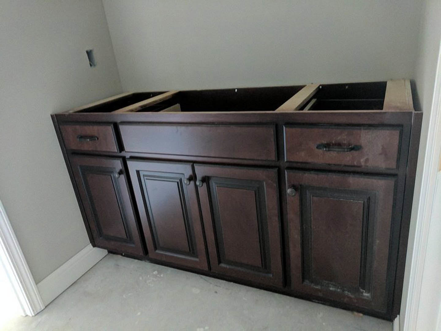 Light wood kitchen cabinet with multiple drawers, set against a white wall, featuring a countertop with a cutout for a sink.